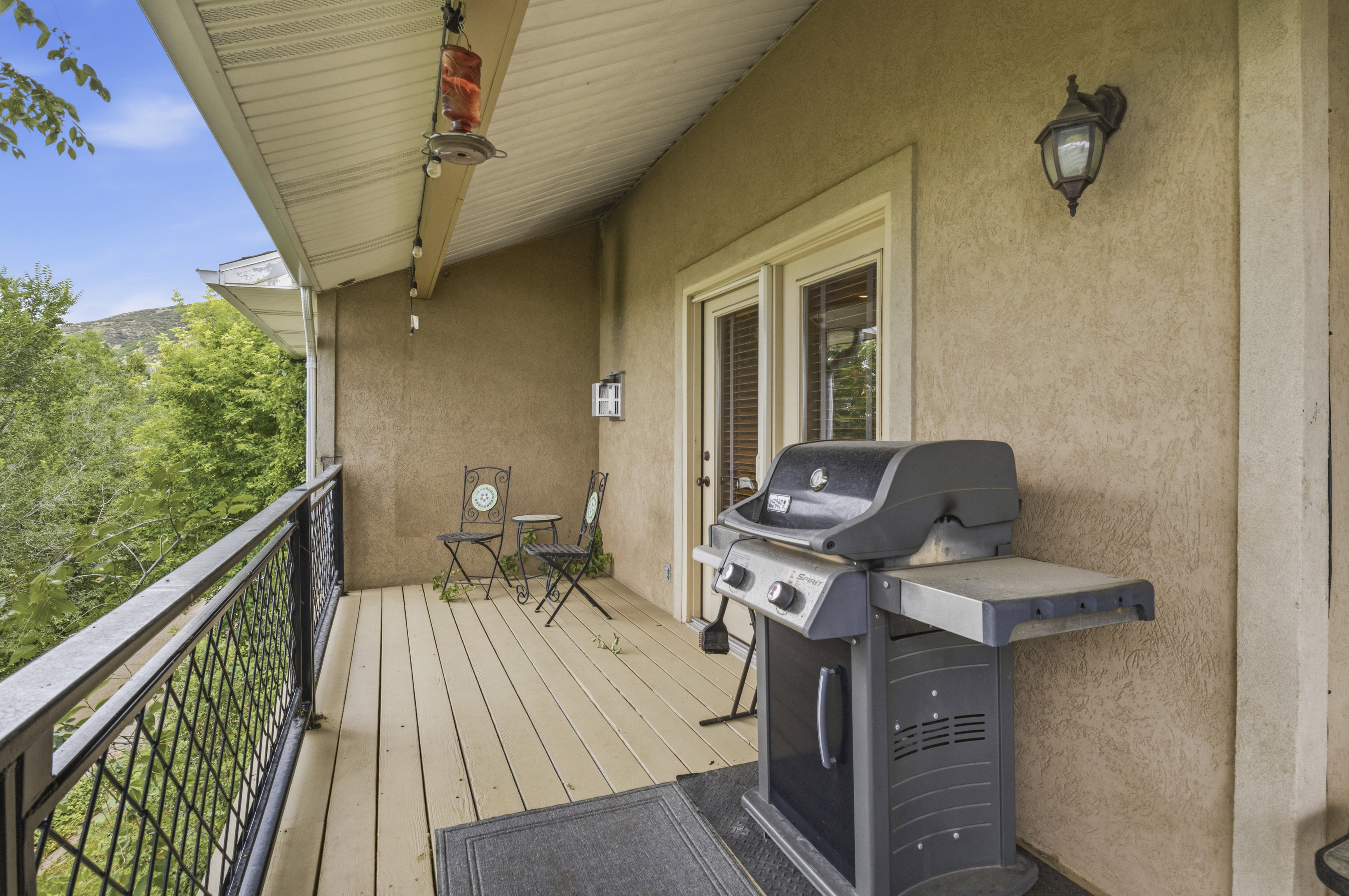 Covered deck featuring a wood-finish floor and black metal railing