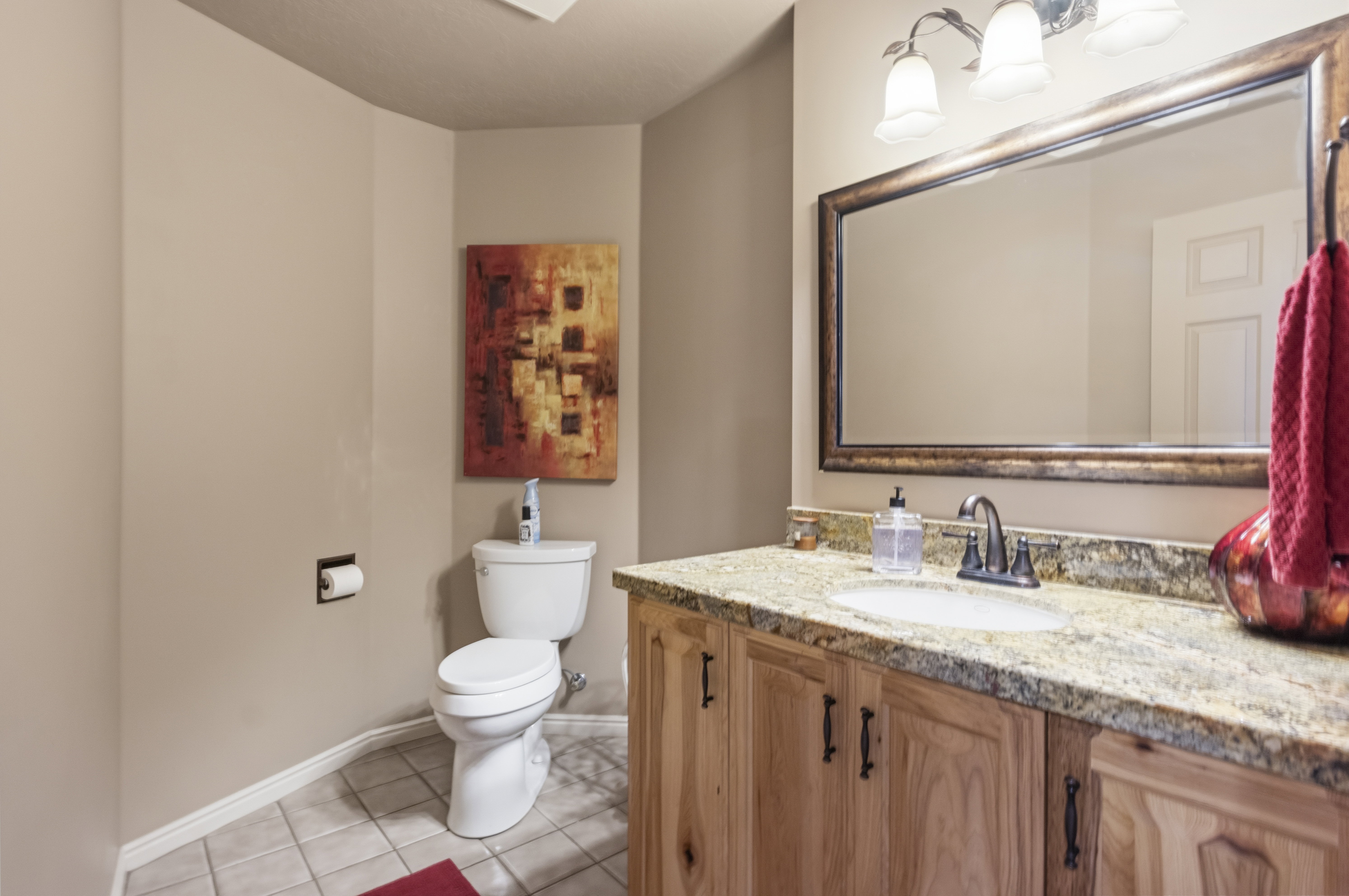 Vanity with a granite countertop, undermount sink, and wood-finish cabinetry featuring dark hardware
