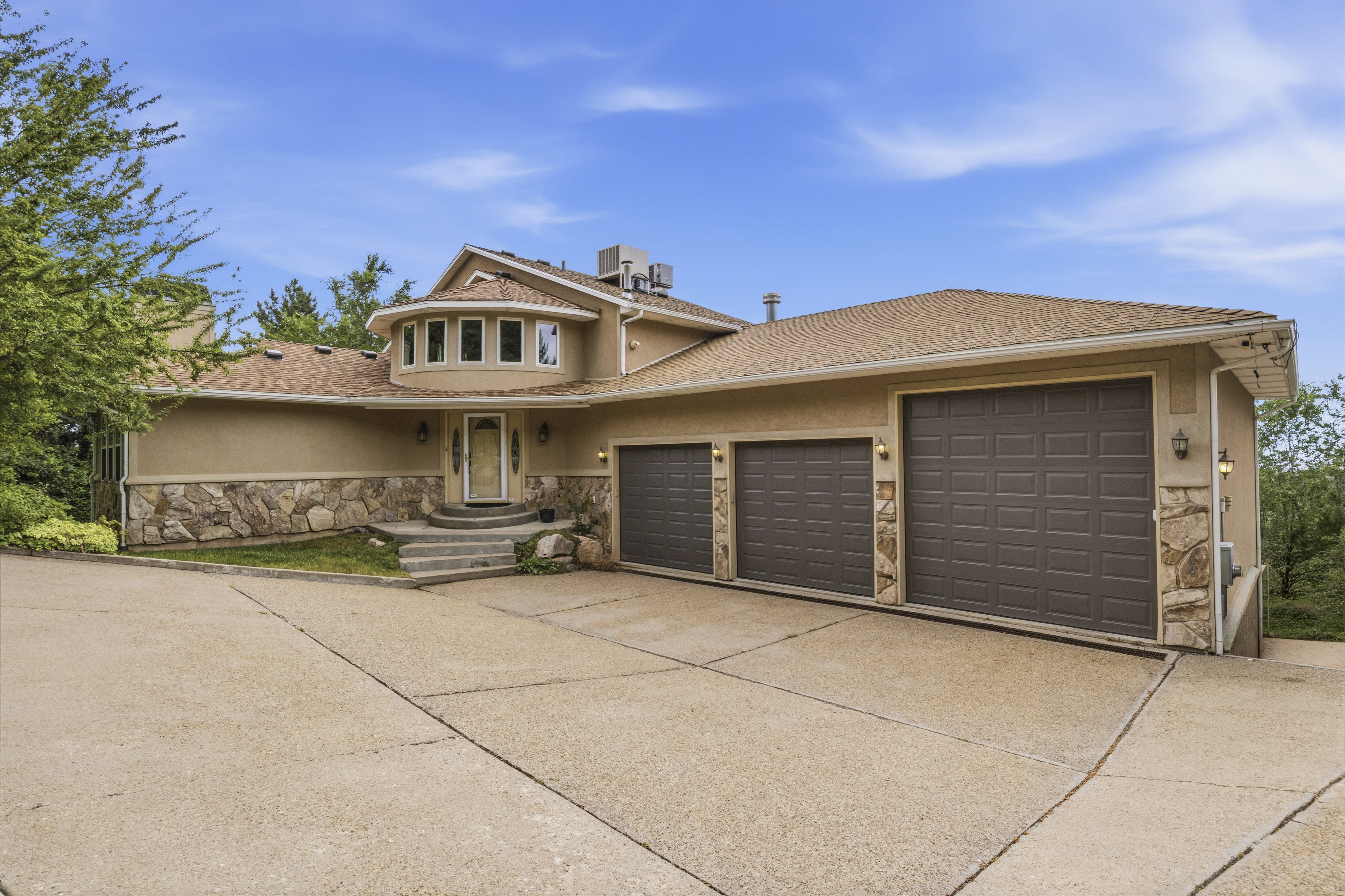 Stucco and stone exterior featuring a prominent rounded bay window with multiple panes