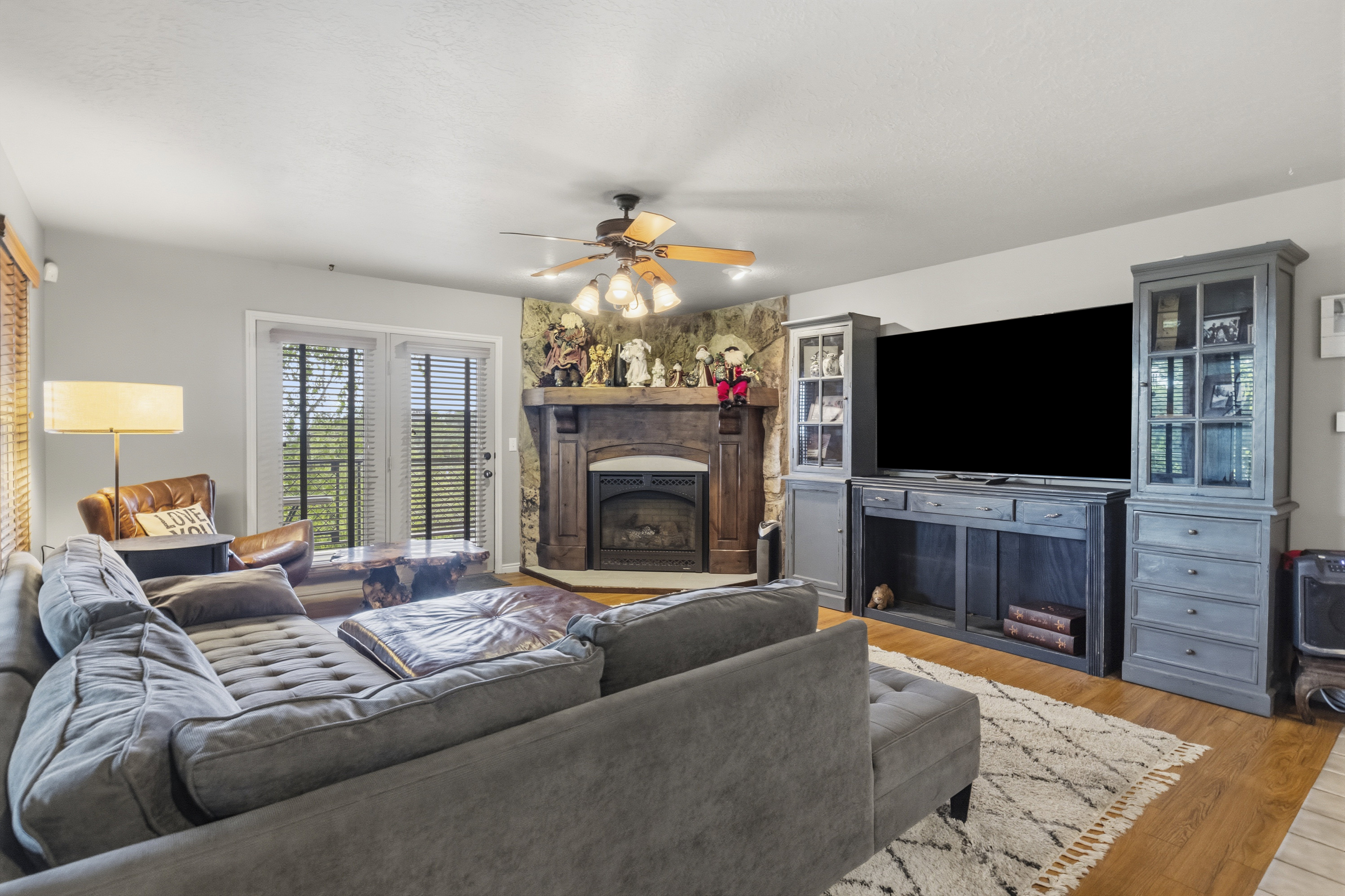 Living area with wood-finish flooring, a stone-surround fireplace with a wood mantle, and double glass-paned doors