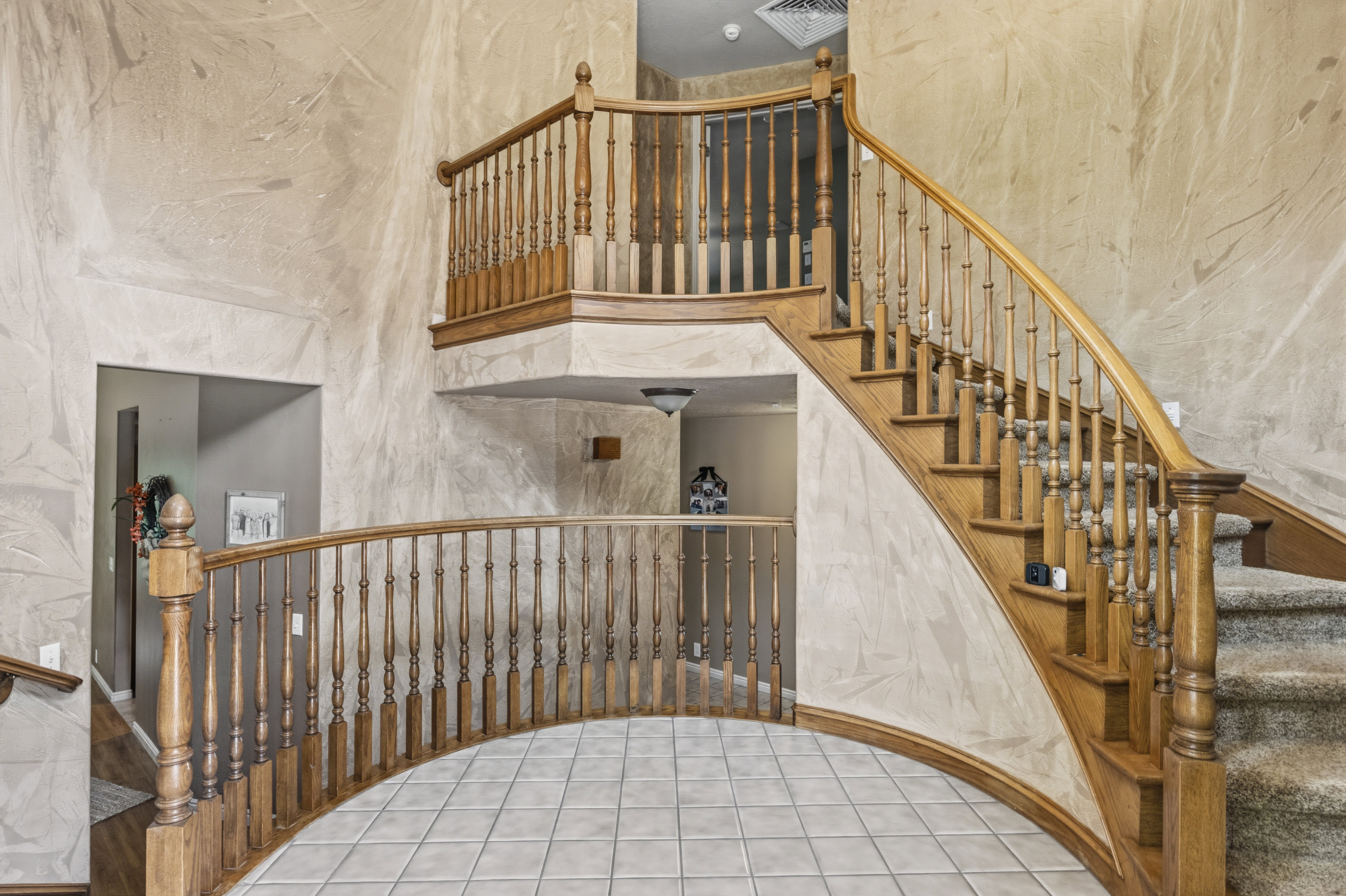 Grand two-story entryway featuring a curved staircase with wood balusters and handrails