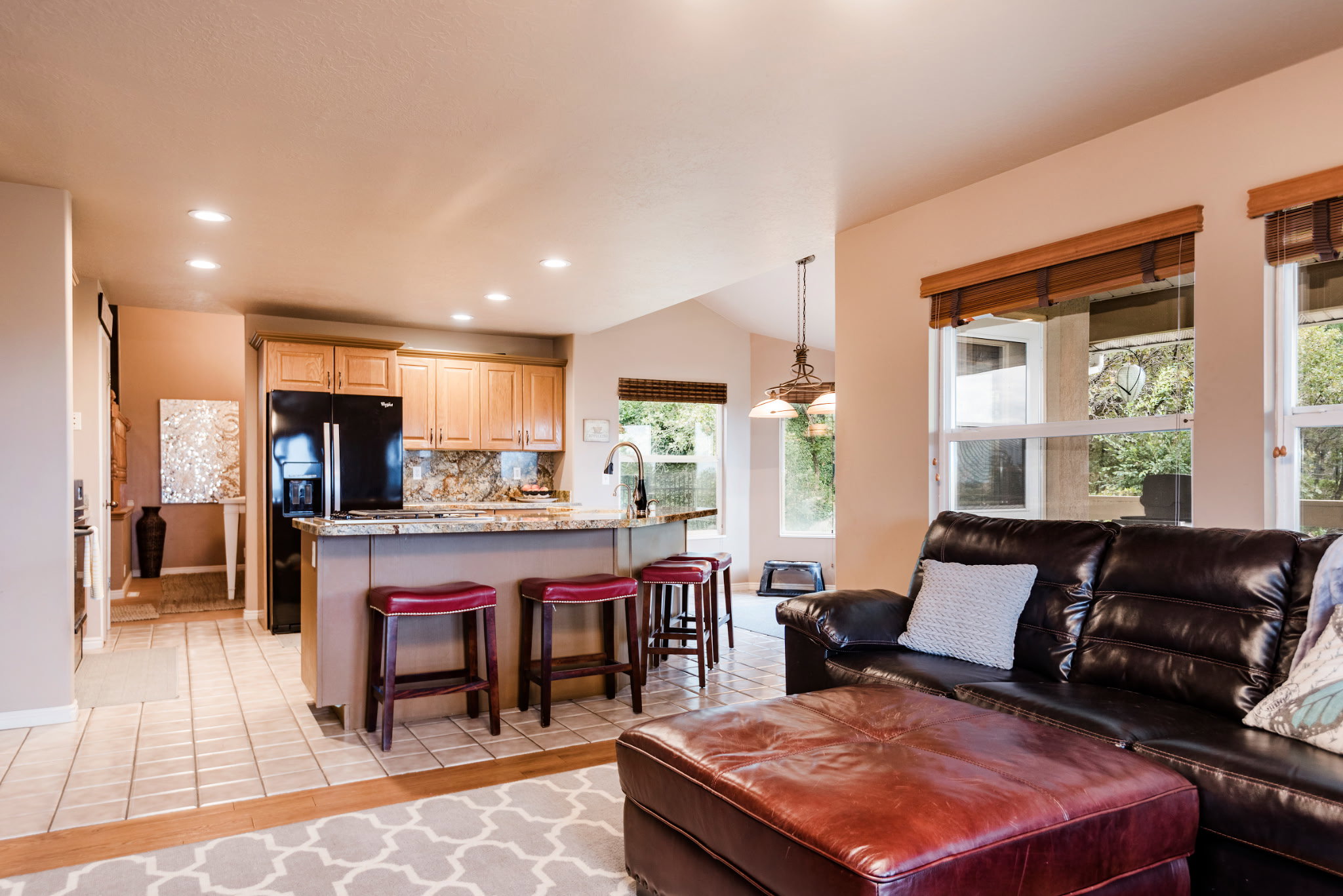 Kitchen featuring light wood cabinetry, stone countertops, and black appliances