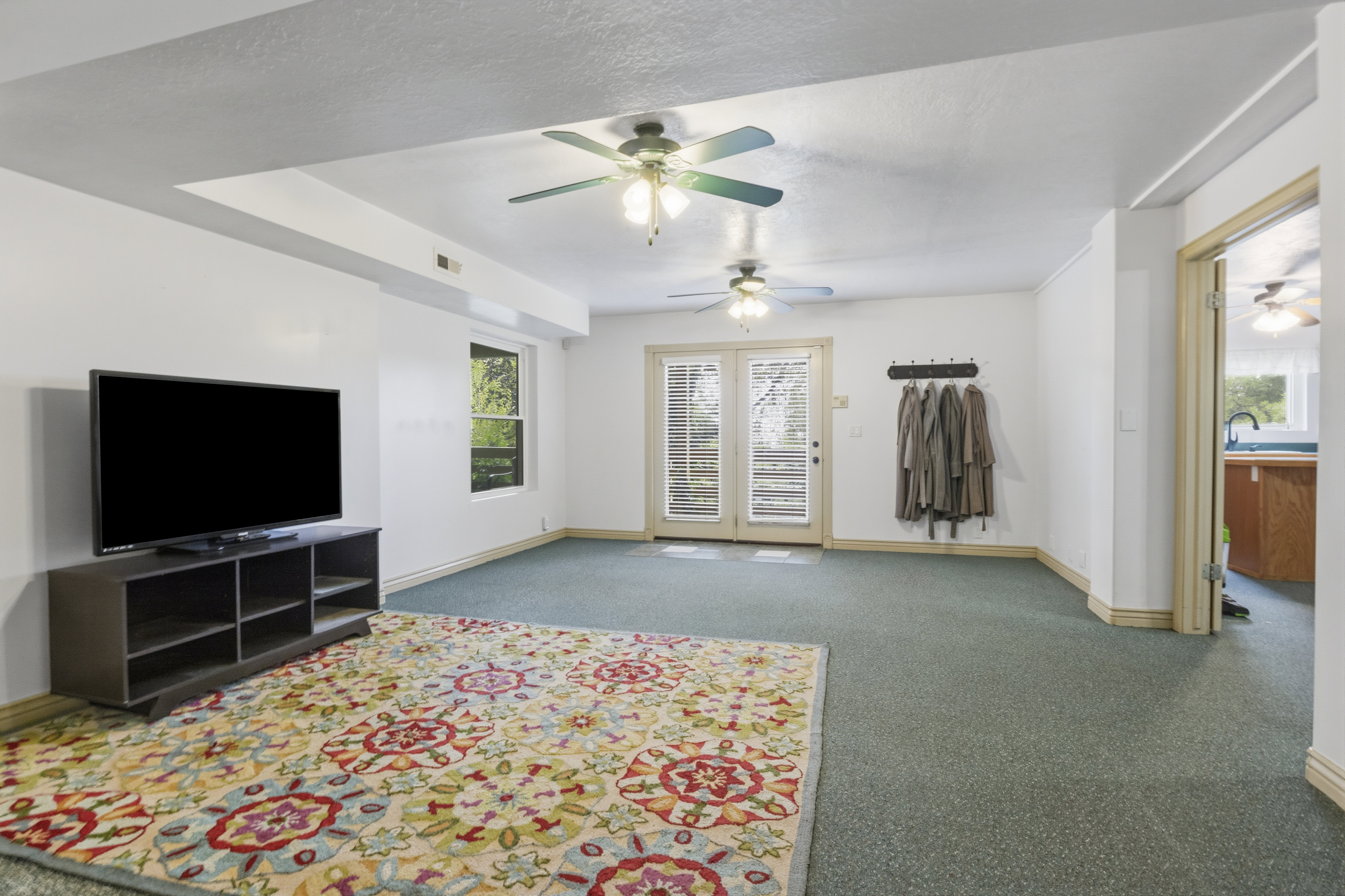 Spacious interior room featuring light-colored walls and green carpeting