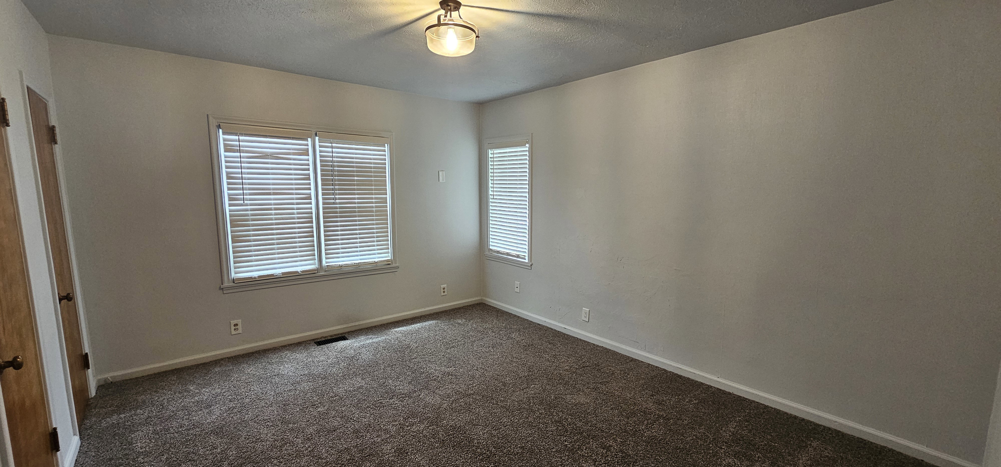Bedroom featuring neutral wall tones and dark carpet flooring