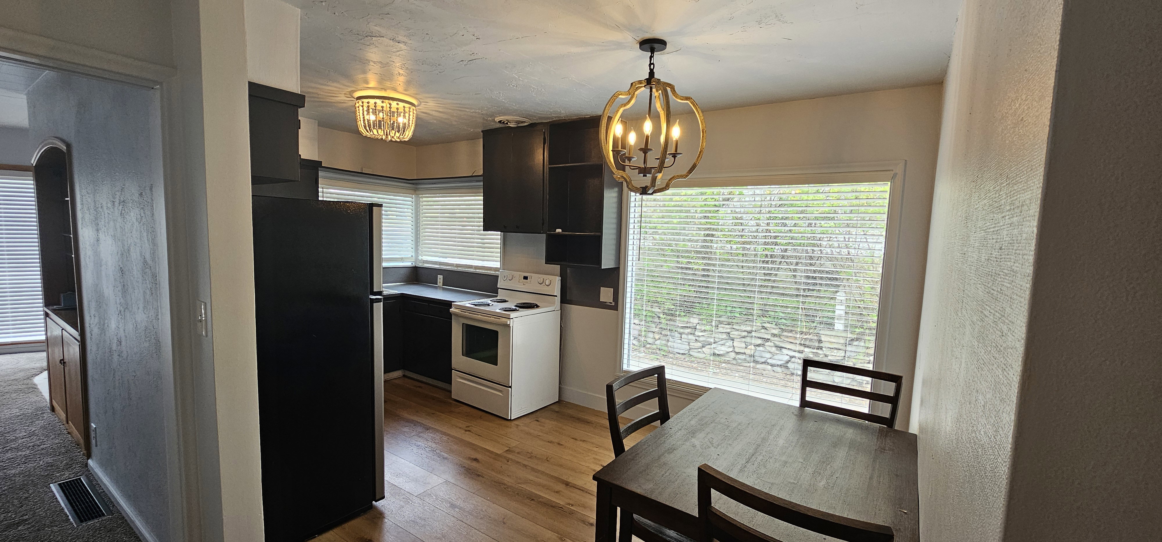 Kitchen area featuring wood-finish flooring, dark cabinetry, and a large window
