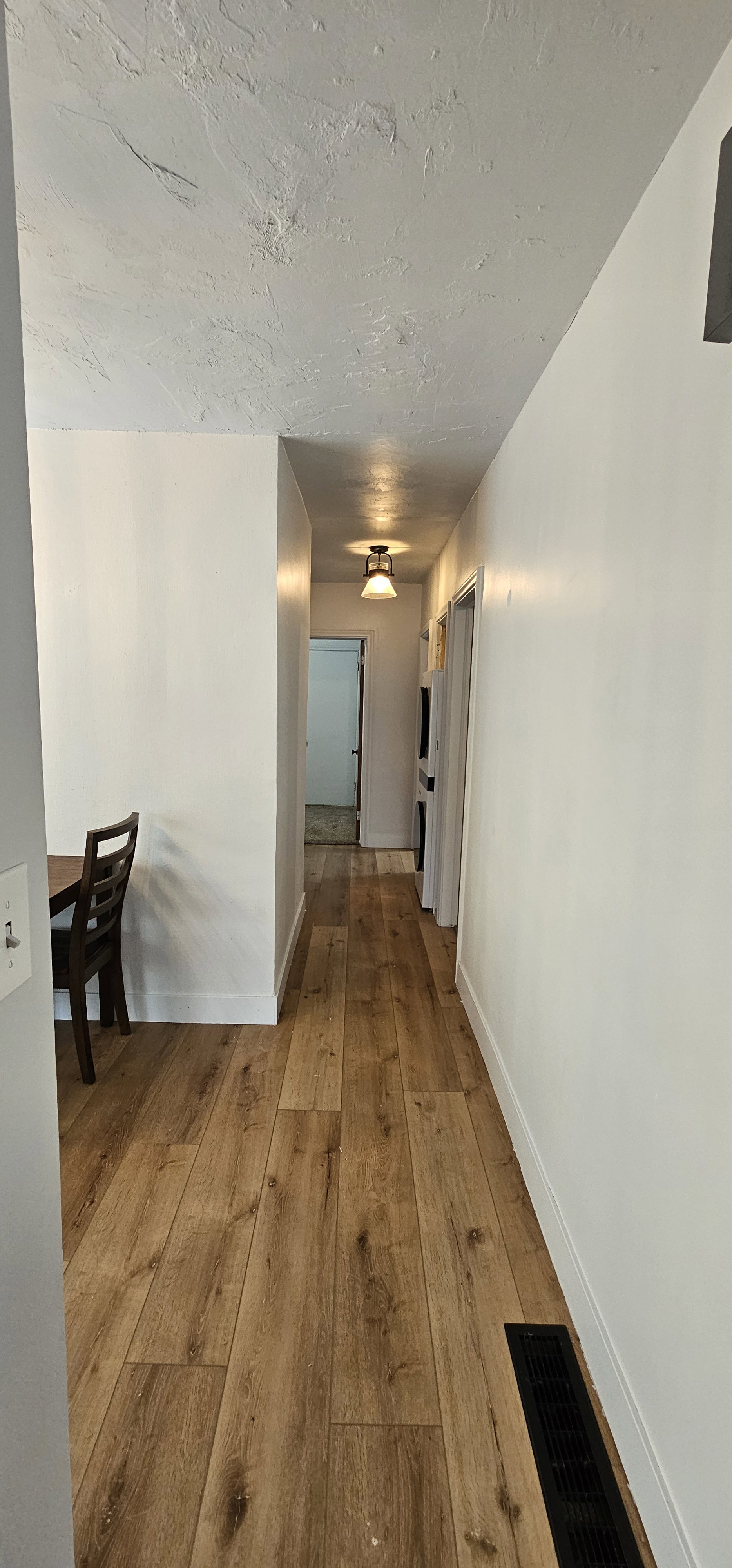 Hallway featuring wood-finish flooring, white painted walls, and a ceiling-mounted light fixture