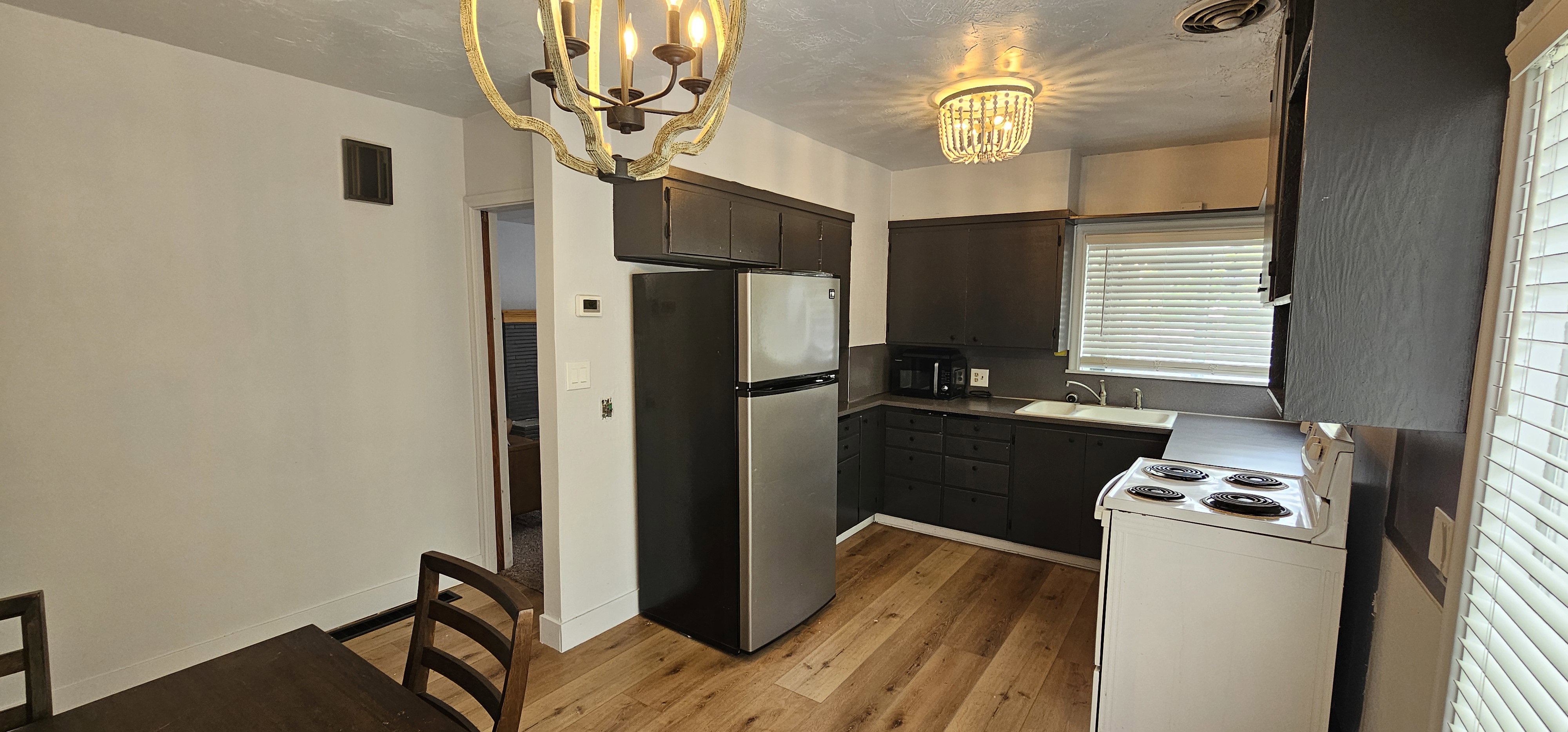 Kitchen featuring wood-finish flooring, dark cabinetry, and light countertops