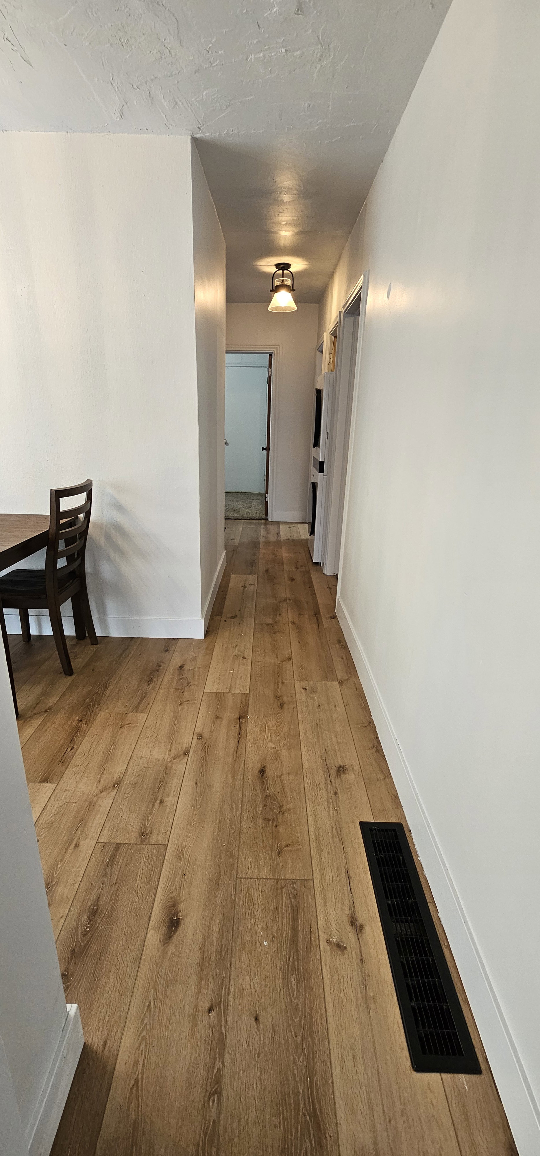 Hallway featuring wood-finish flooring, white walls, and a ceiling-mounted light fixture