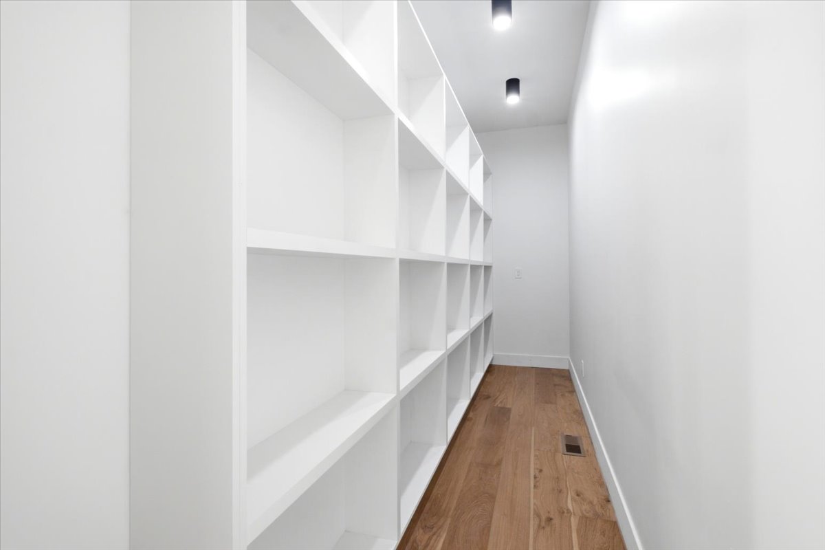 Built-in white shelving system featuring multiple cubbies, wood-finish flooring, and recessed ceiling lighting