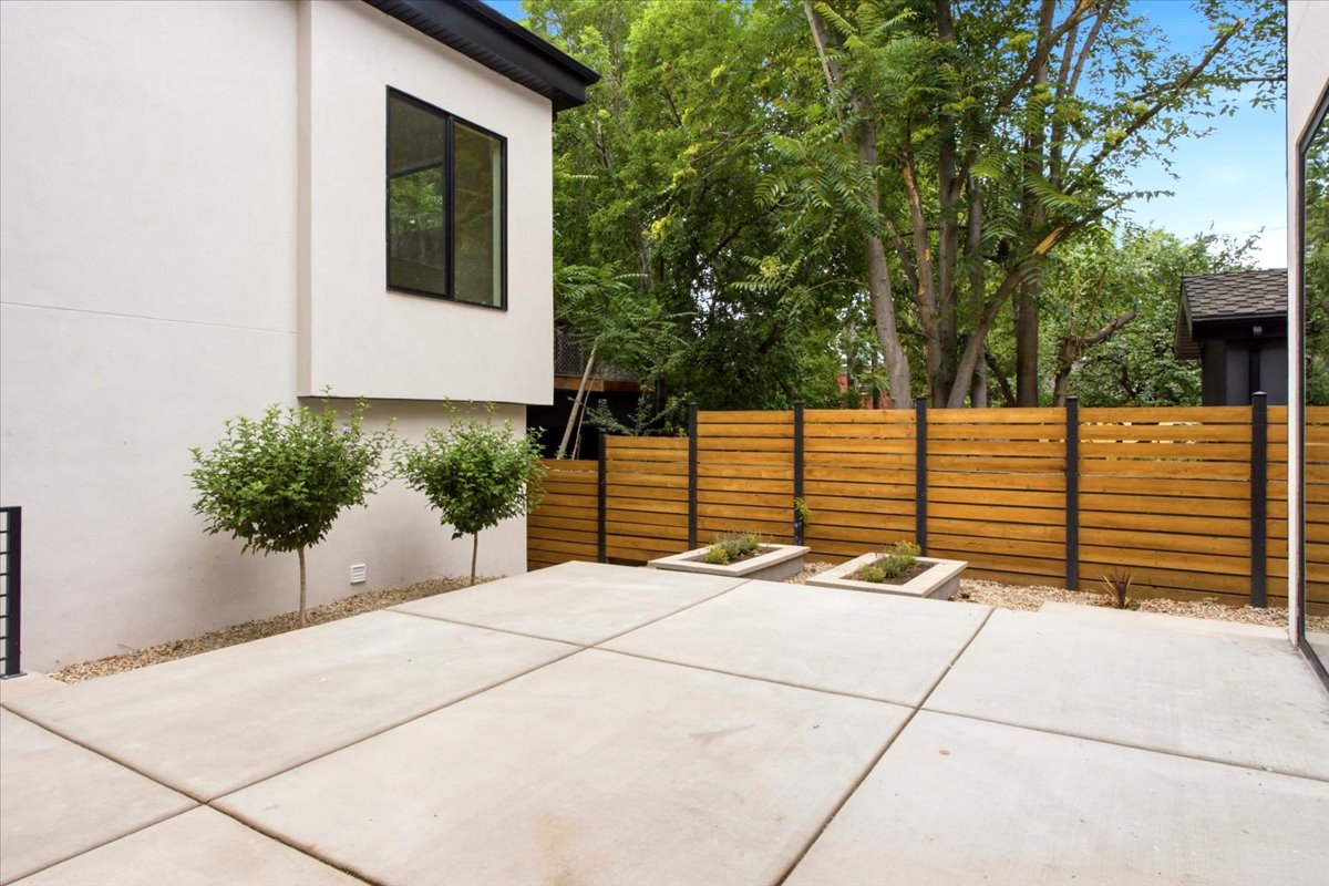 Spacious concrete patio featuring horizontal wood fencing with black posts