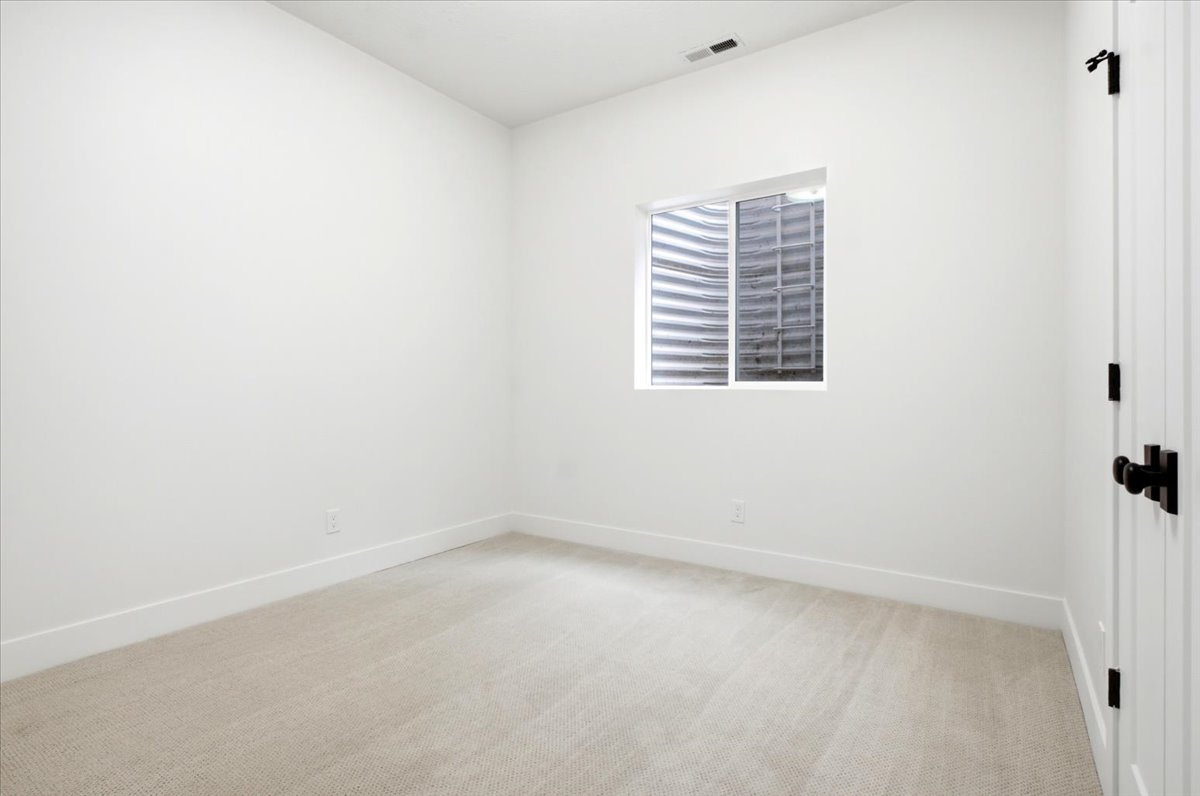 Carpeted room featuring a single window, white walls, and a white door with black hardware