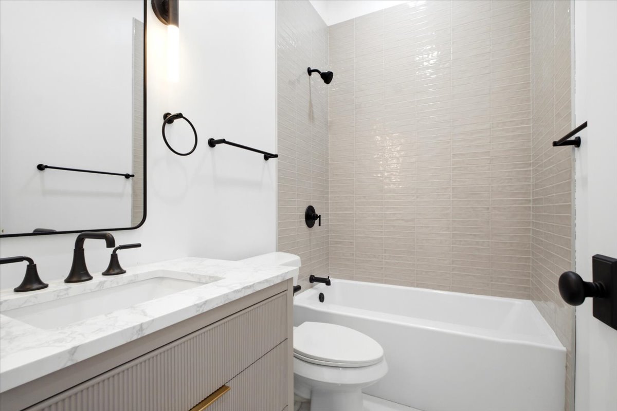 Contemporary bathroom featuring a light gray vanity with a stone countertop, an undermount sink, and matte black fixtures