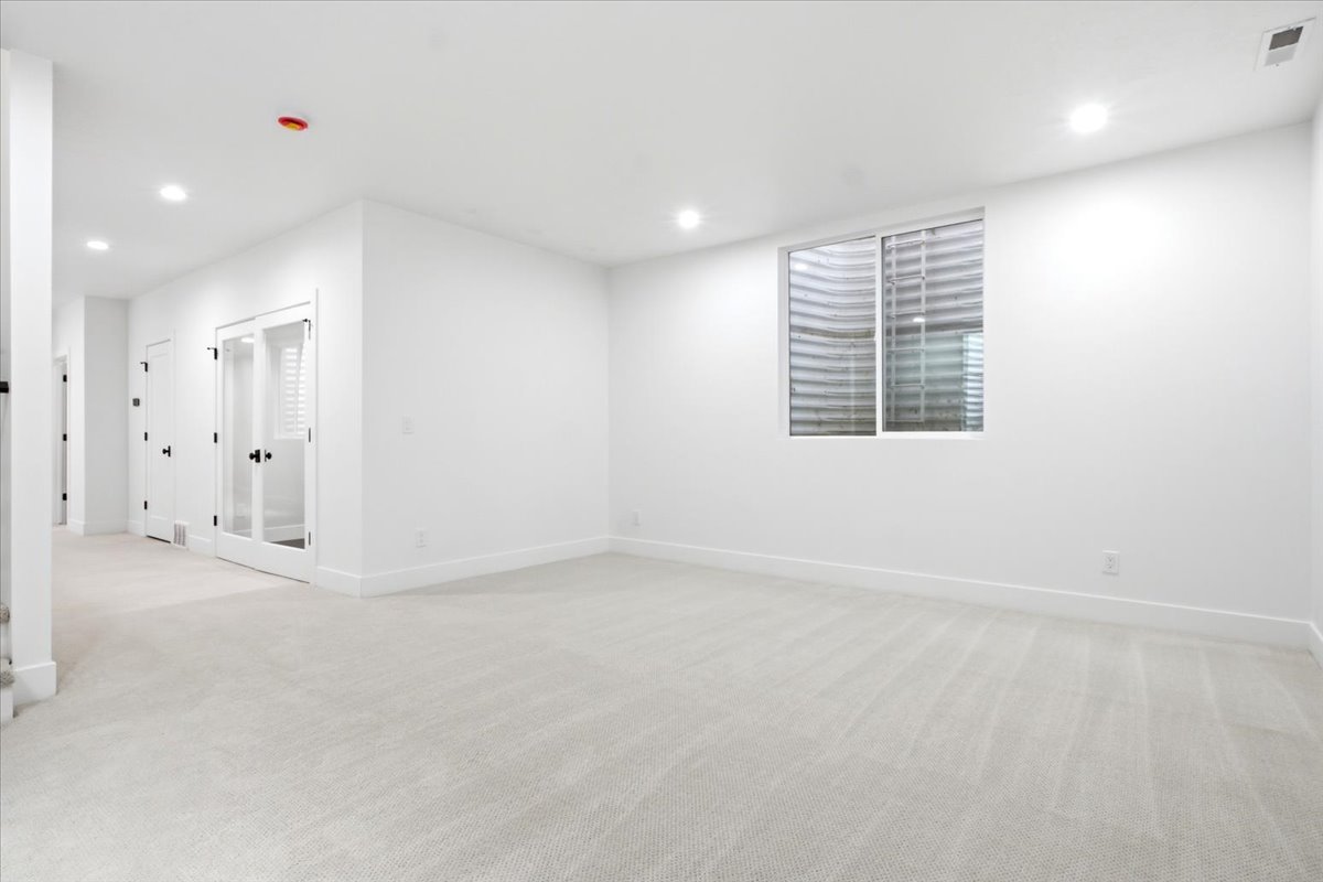 Expansive room featuring light gray carpeting and bright white walls
