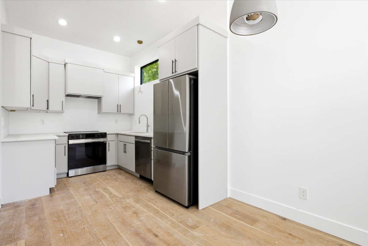 Modern kitchen featuring light-toned cabinetry, light countertops, and stainless-steel appliances