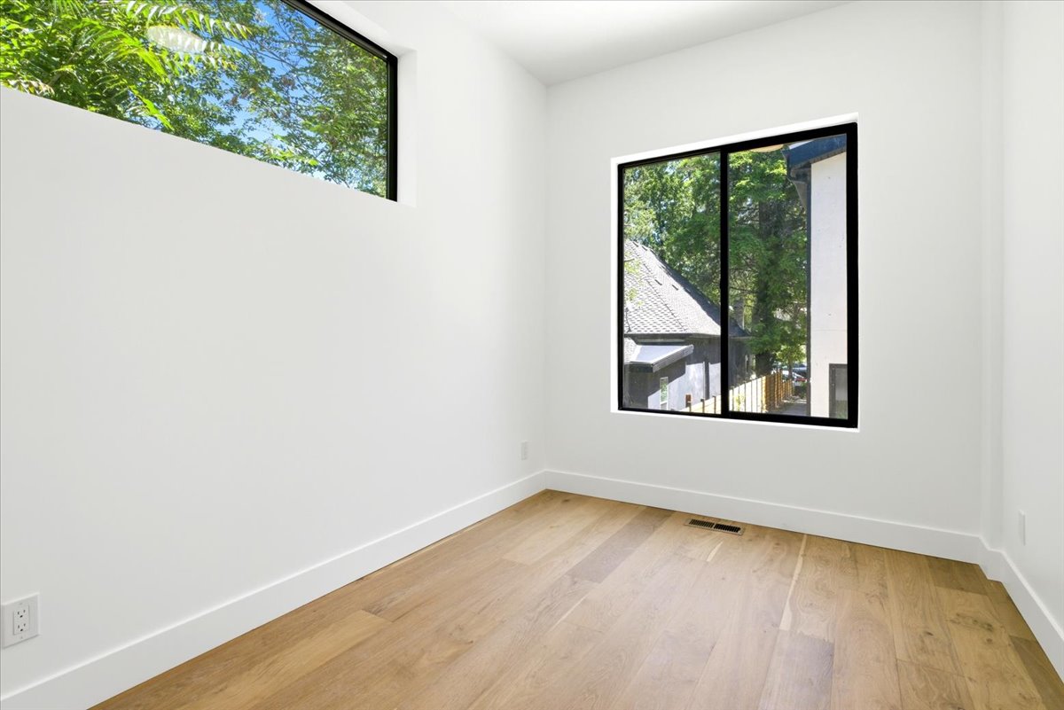 Room with light wood-finish flooring, white baseboards, and white walls
