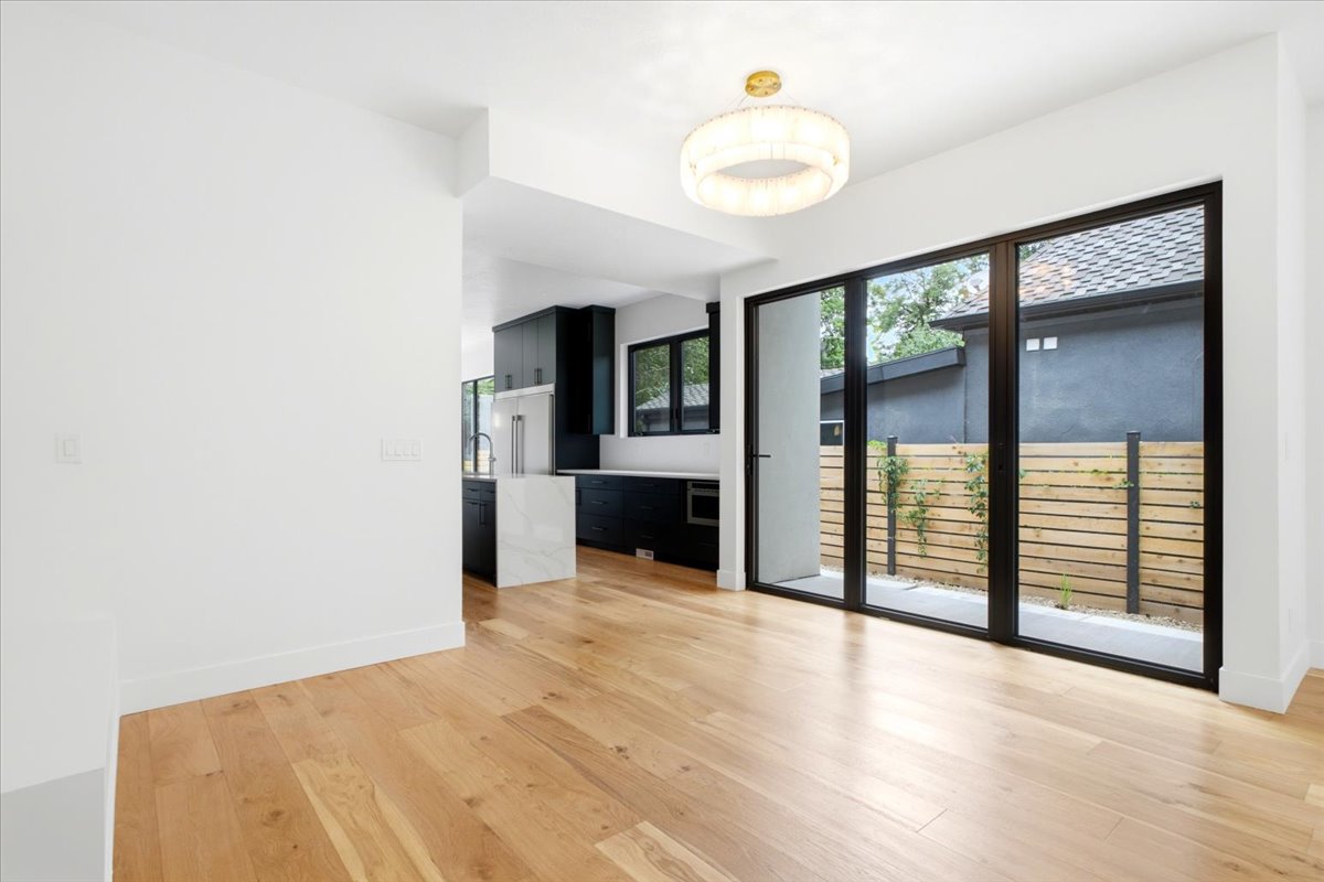 Open concept living area featuring wood-finish flooring, a contemporary chandelier, and expansive black-framed glass patio doors
