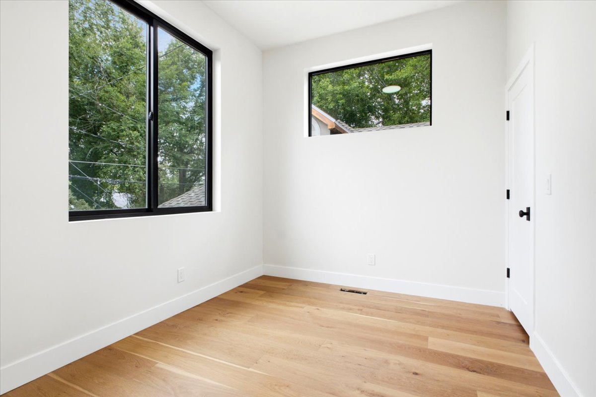 bedroom featuring wood-finish flooring, white walls, and a white door with matte black hardware