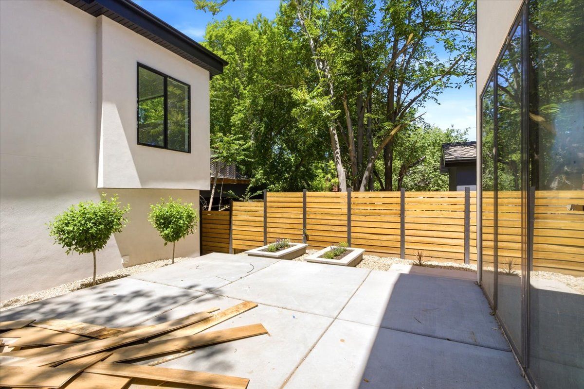 Private outdoor patio area featuring concrete paving, a horizontal slat wood privacy fence, and integrated planters