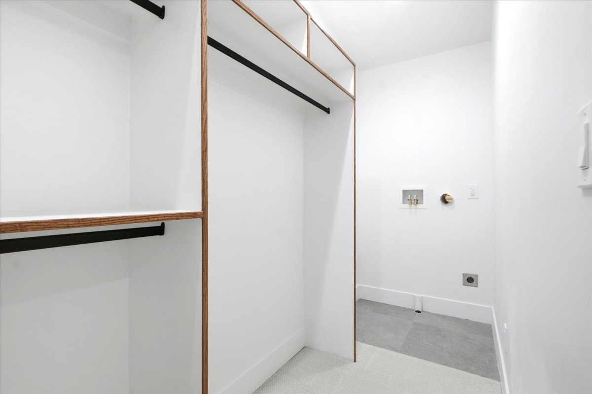 Primary Custom closet system featuring wood-finish framing and integrated shelving. Washer and dryer hookups