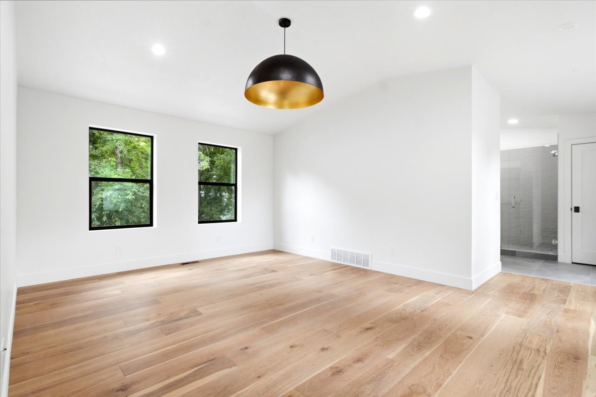 Primary Bedroom featuring wood-finish flooring, recessed lighting, and a contemporary black and gold pendant light fixture