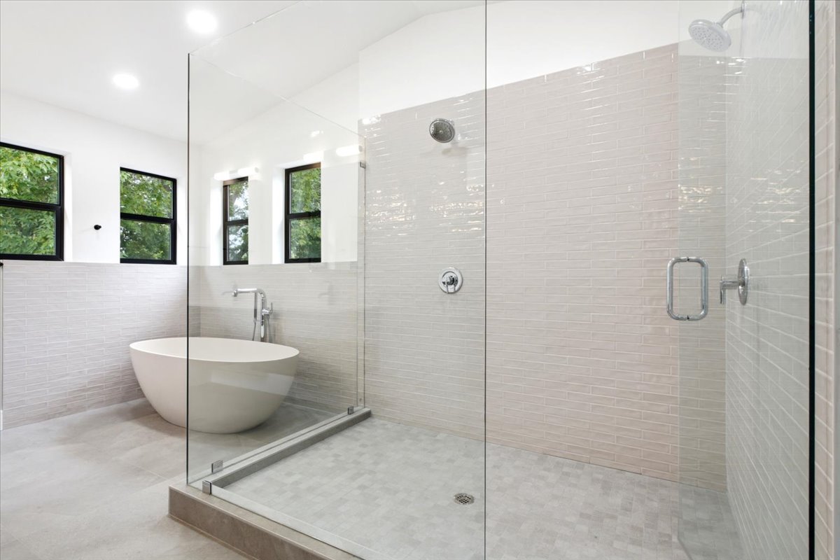 Contemporary bathroom featuring a freestanding soaking tub, glass-enclosed shower with subway tile walls, dual shower heads, and recessed lighting