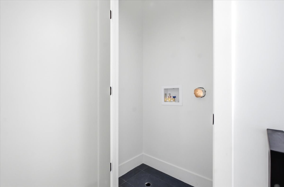 Dedicated laundry area featuring a wall-mounted utility box, dark tile flooring, and white baseboards