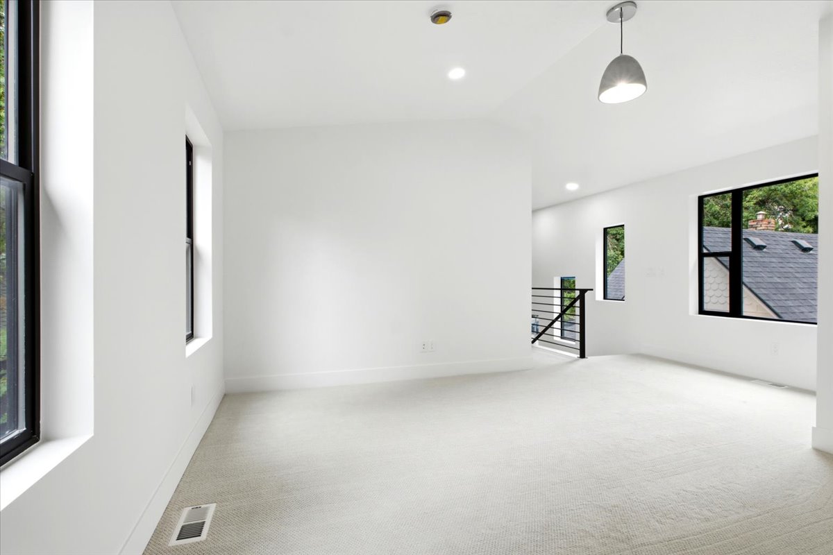 Expansive room featuring light-toned carpeting and multiple black-framed windows