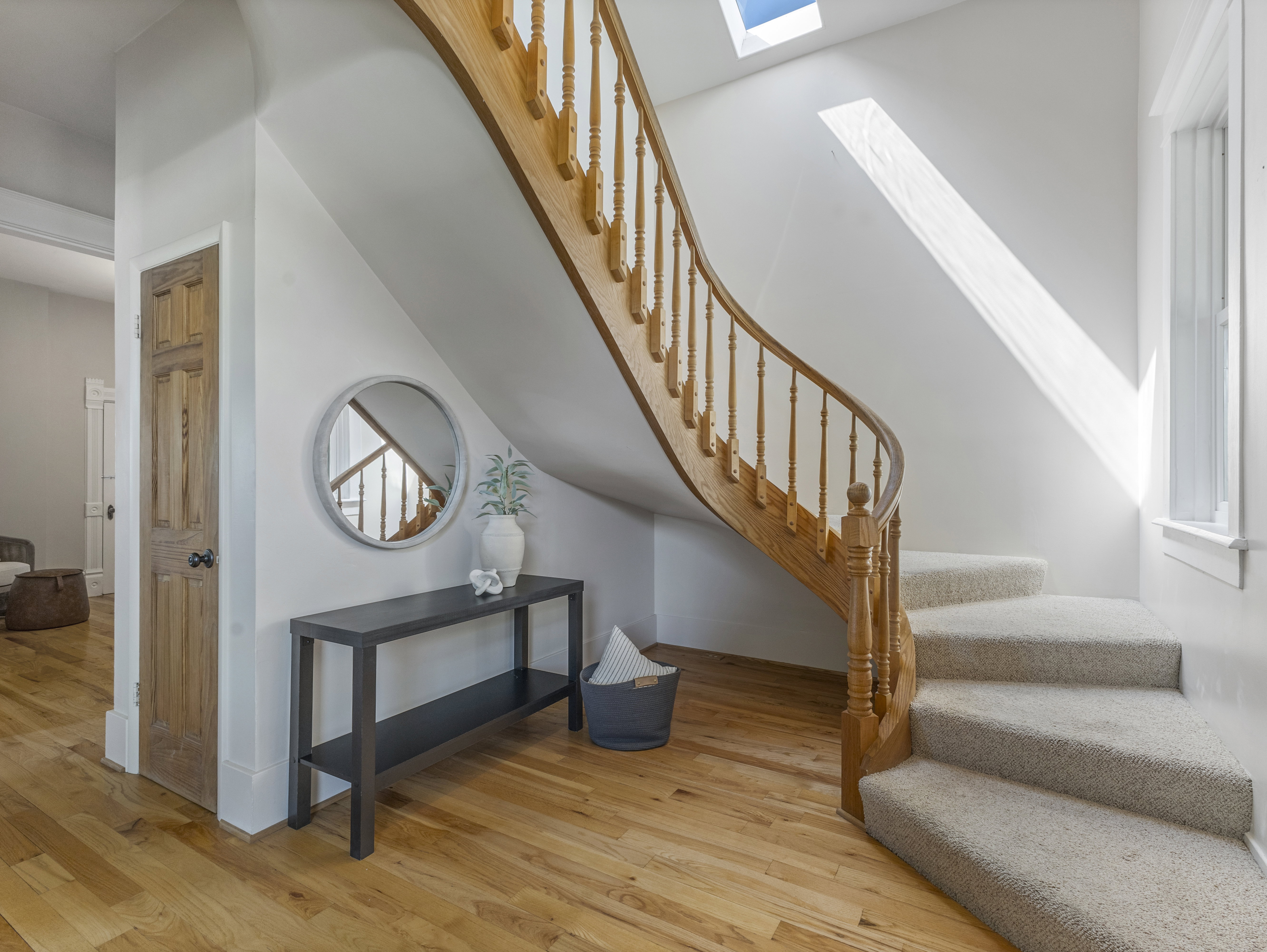 Curved wooden staircase with balusters, carpeted treads, and natural wood-finish flooring
