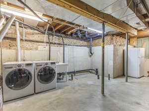 Laundry area featuring a utility sink, concrete flooring, exposed joists, and a partial stone foundation