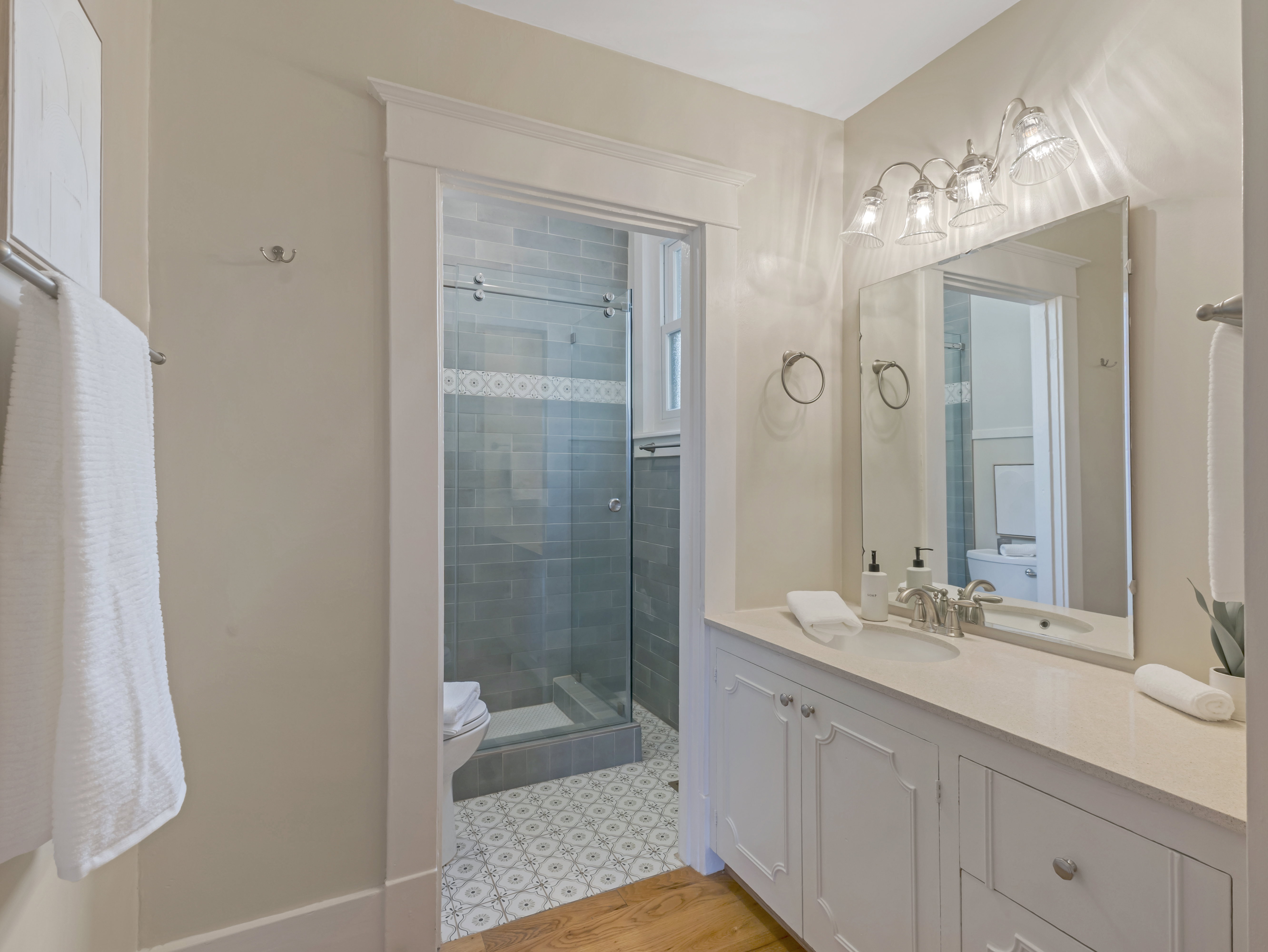 Vanity with white cabinetry and light-toned countertop, featuring a single basin and chrome fixtures