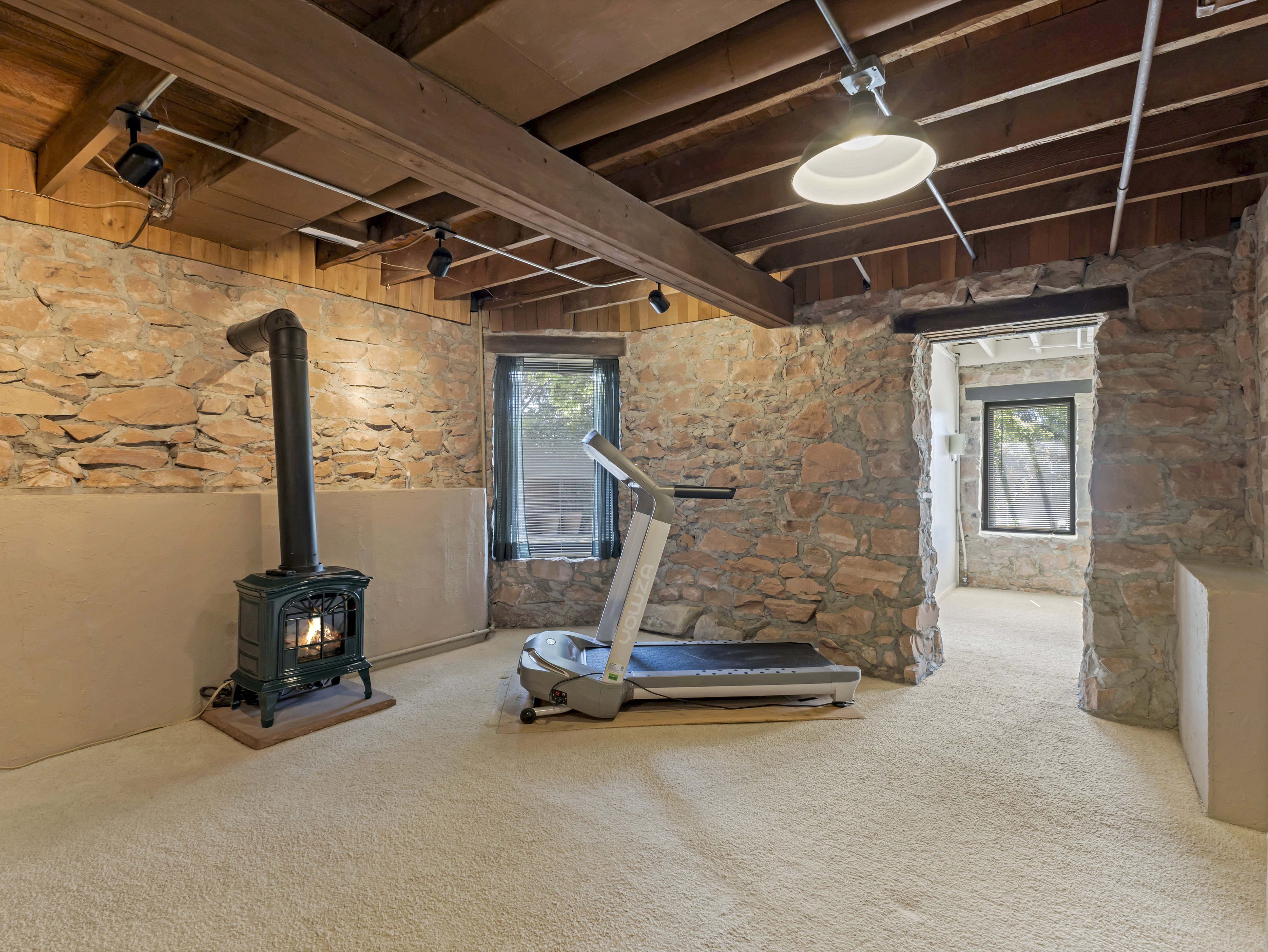 Exposed wood beam ceiling with track lighting and recessed fixture, complemented by stone wall finishes