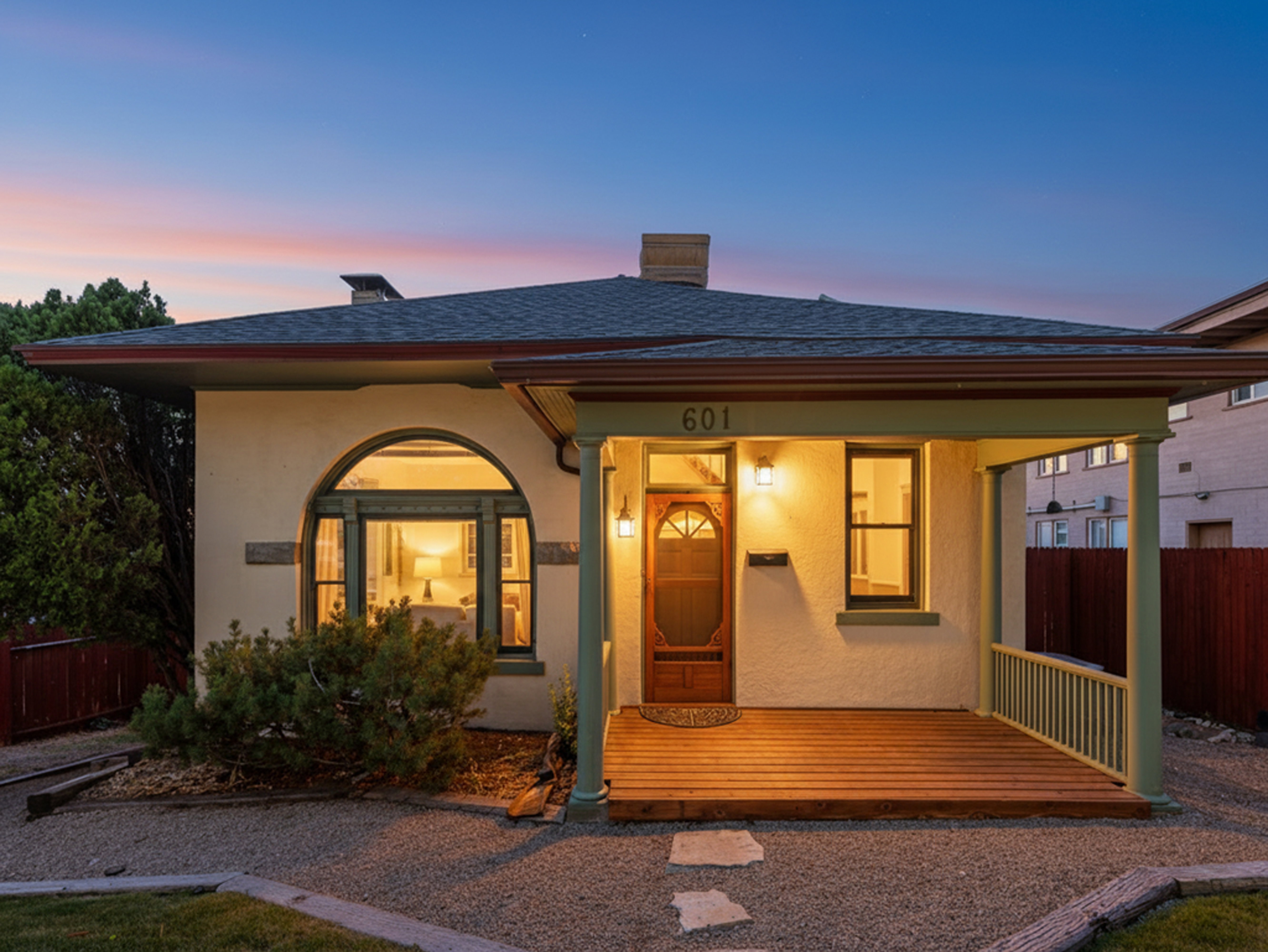 Stucco exterior featuring a wood-plank front porch and gravel landscaping