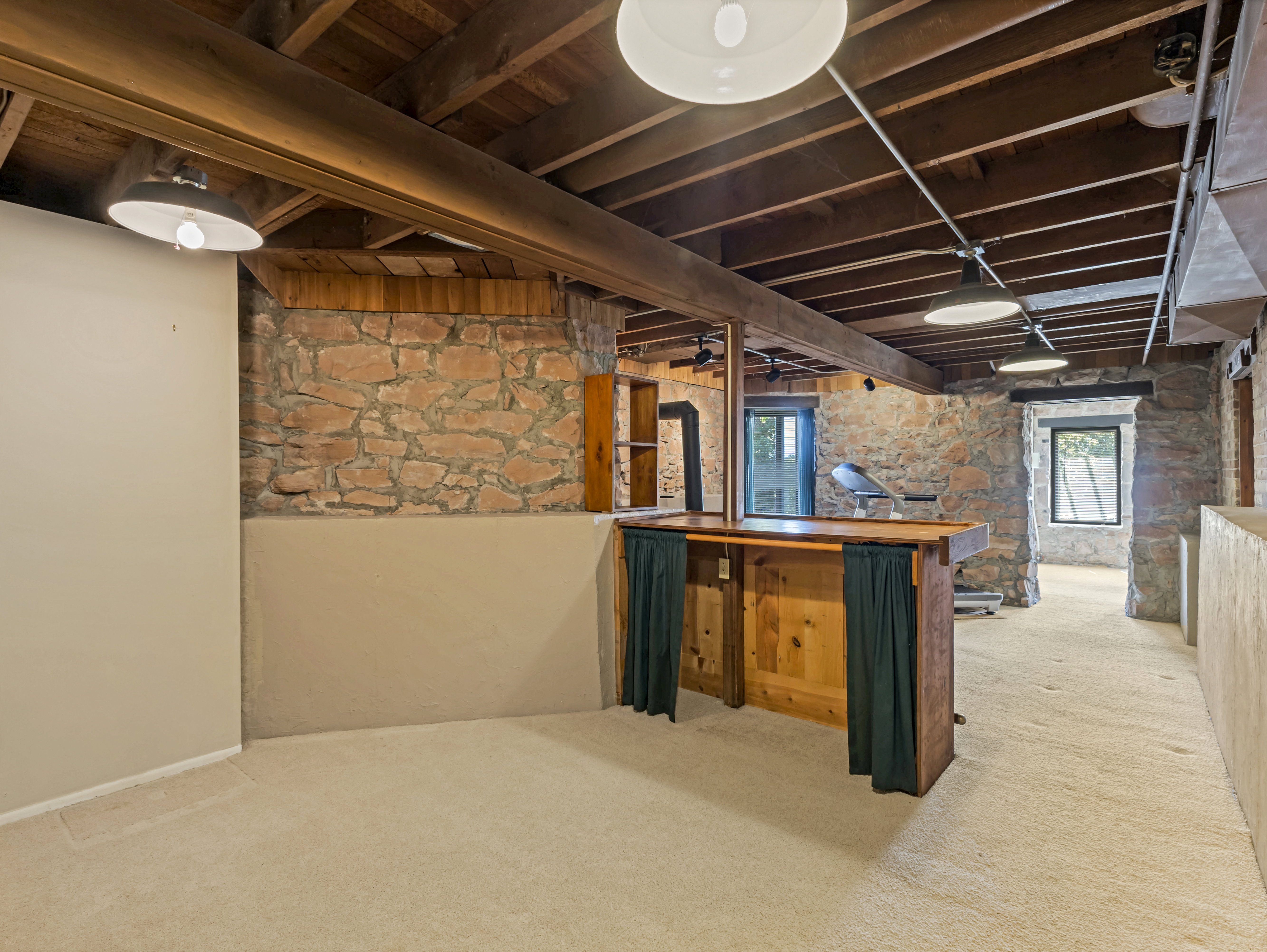 Recreation room featuring a built-in wooden bar, exposed stone walls, recessed lighting, and carpet flooring
