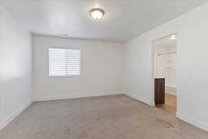 Carpeted room with a single window, white walls, and a ceiling-mounted light fixture