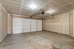 Spacious garage featuring a concrete floor, two overhead lights, and a white paneled garage door with an automatic opener
