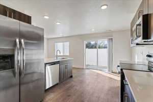 Modern kitchen featuring stainless steel appliances, wood-finish flooring, recessed lighting, white countertops, and contemporary cabinetry