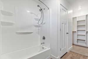 White acrylic tub and shower combination with chrome fixtures and integrated shelving