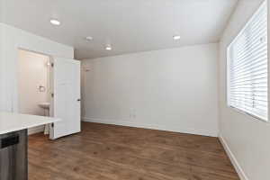 Spacious interior featuring wood-finish flooring, recessed lighting, and a window with horizontal blinds