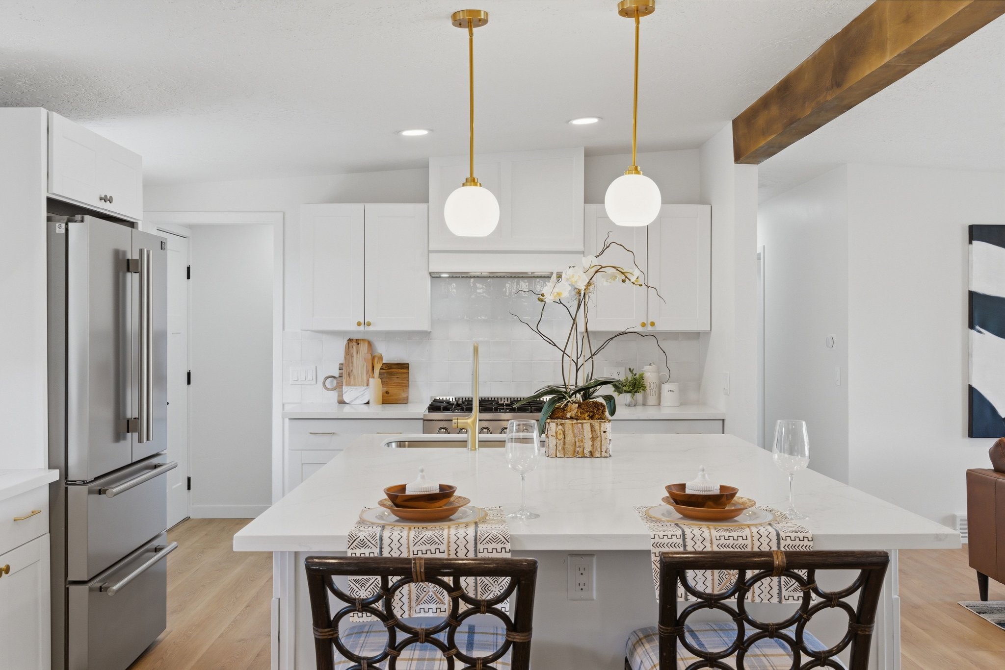 Contemporary kitchen featuring white cabinetry, a large center island with seating, stainless steel appliances, and gold-toned pendant lighting