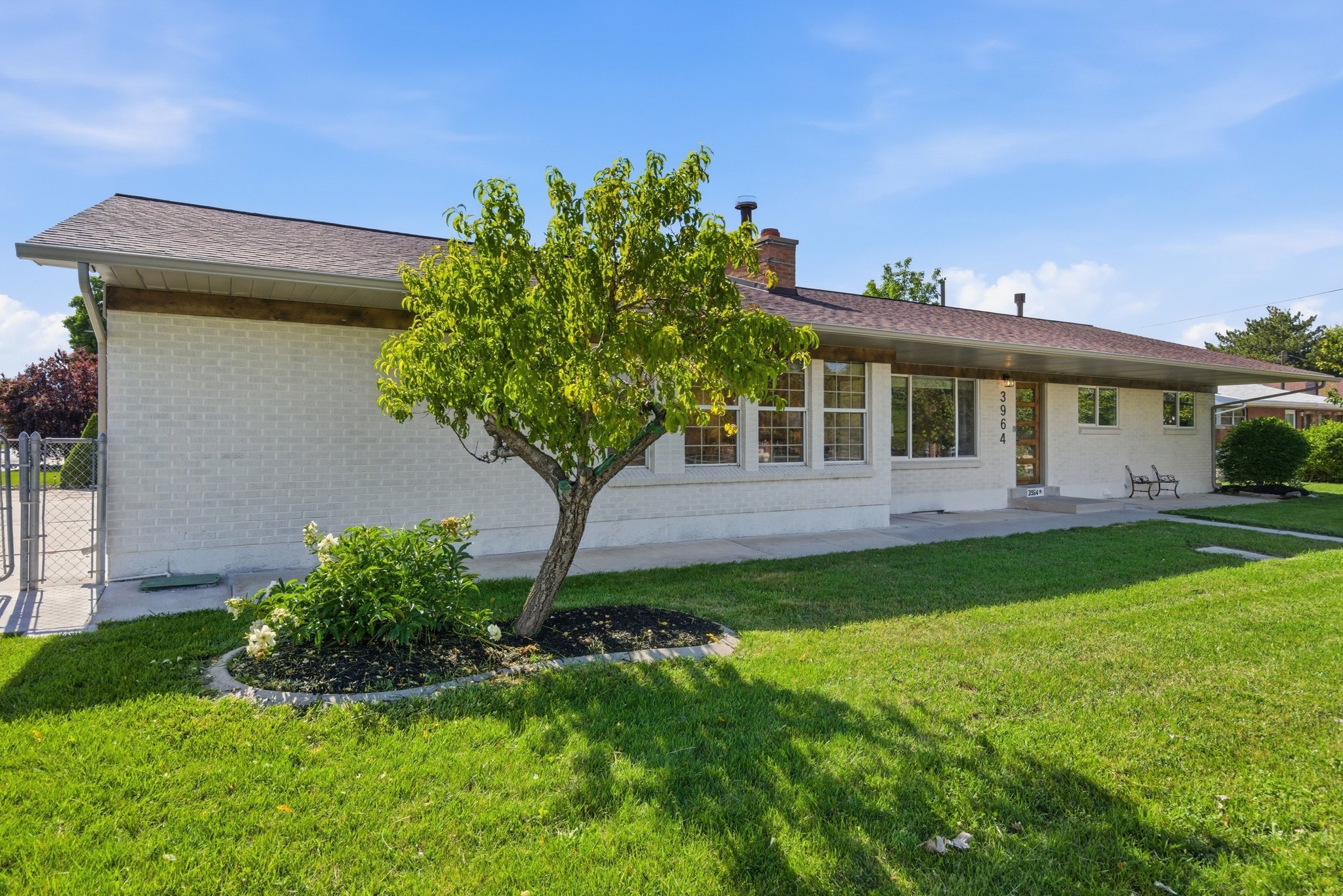 Ranch-style exterior featuring painted brick, a brown shingle roof, and multiple windows