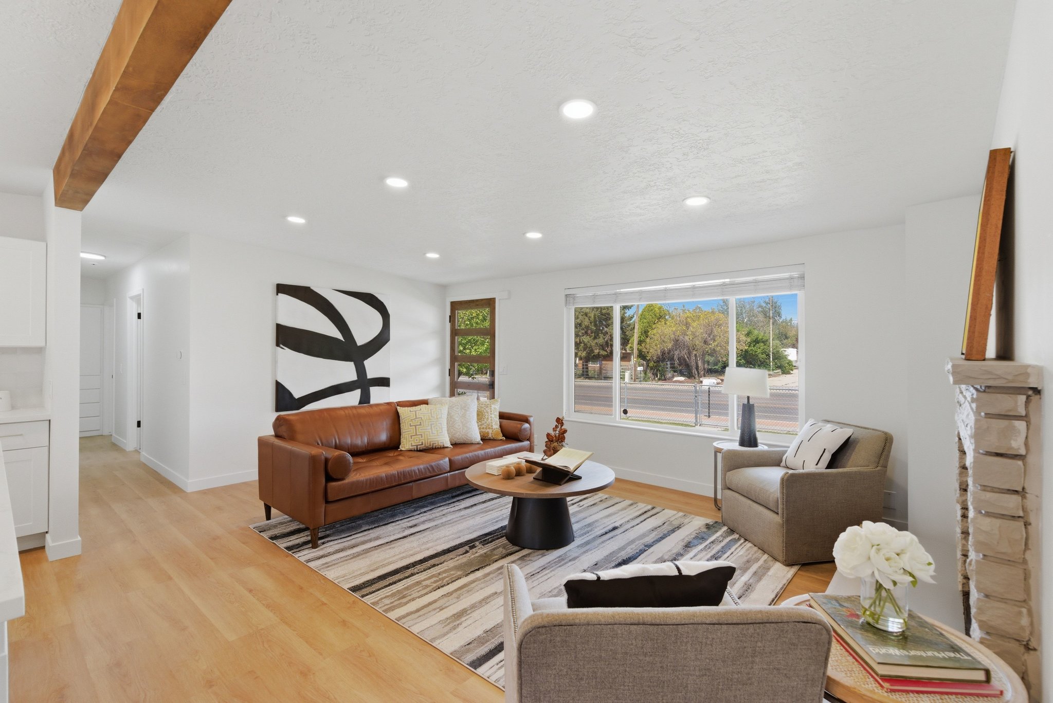Living area featuring wood-finish flooring, a stone-clad fireplace, and recessed lighting