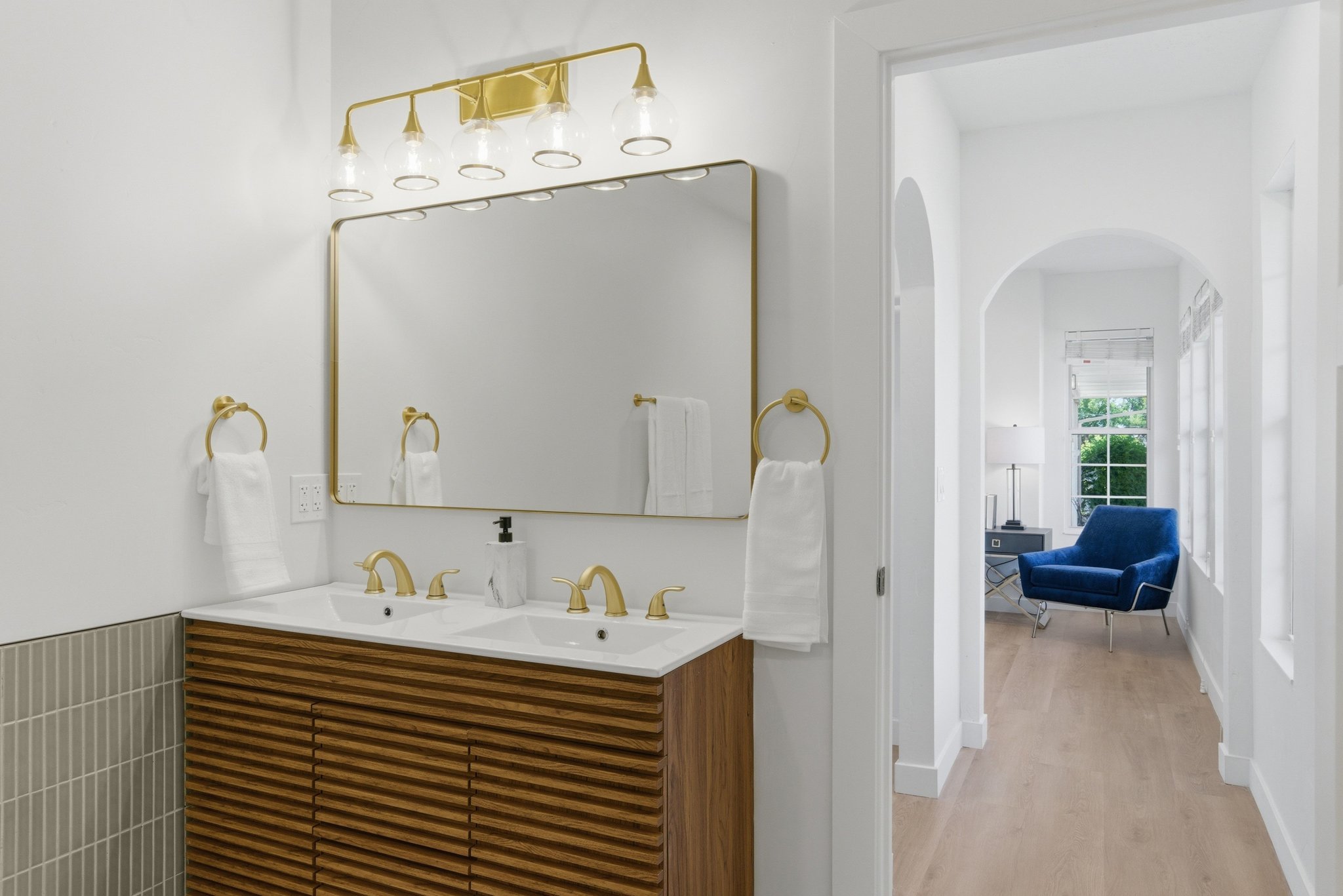 Dual vanity with gold-tone hardware, rectangular mirror, and decorative light fixture