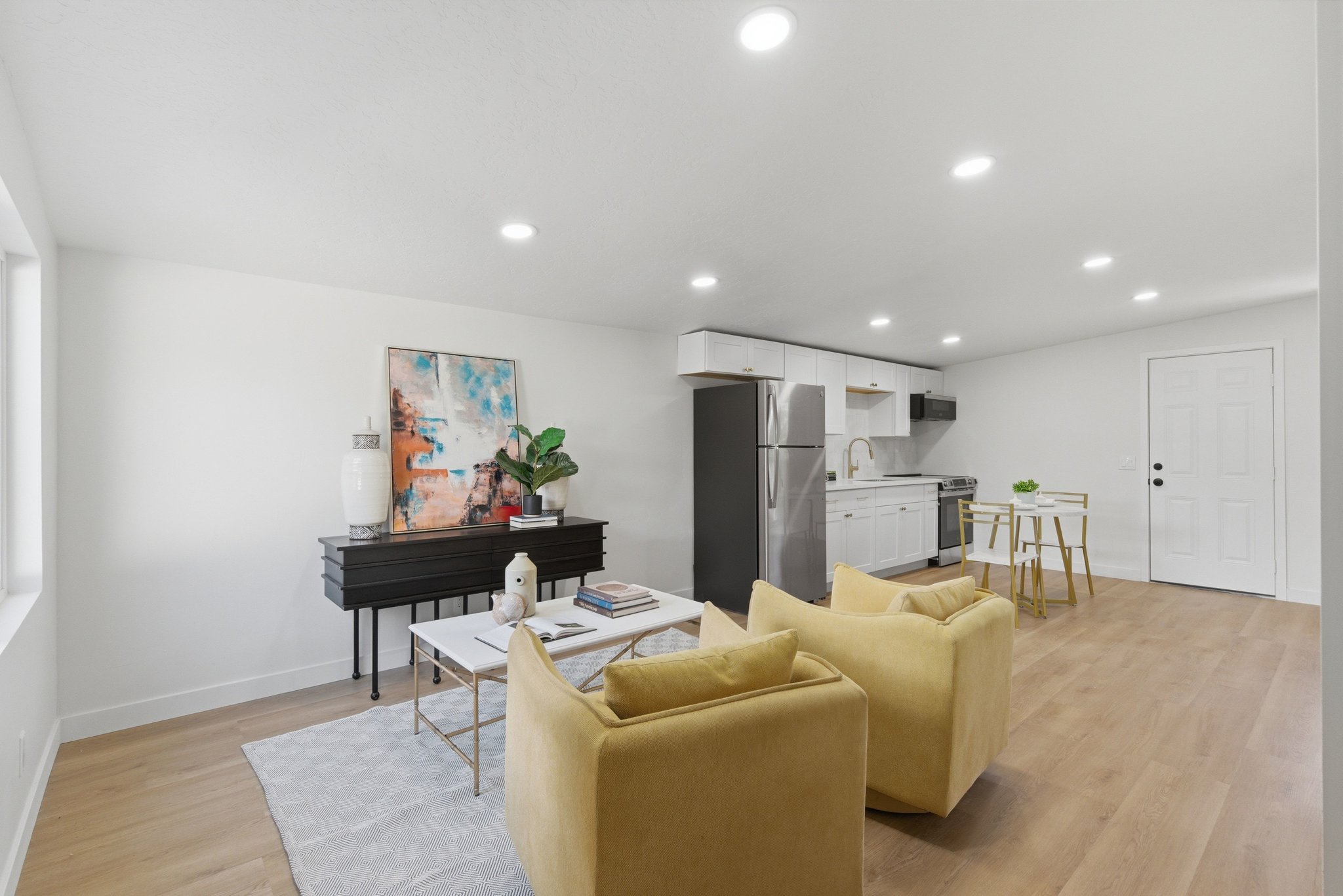 Open-concept living area featuring light wood-finish flooring, recessed lighting, and white walls