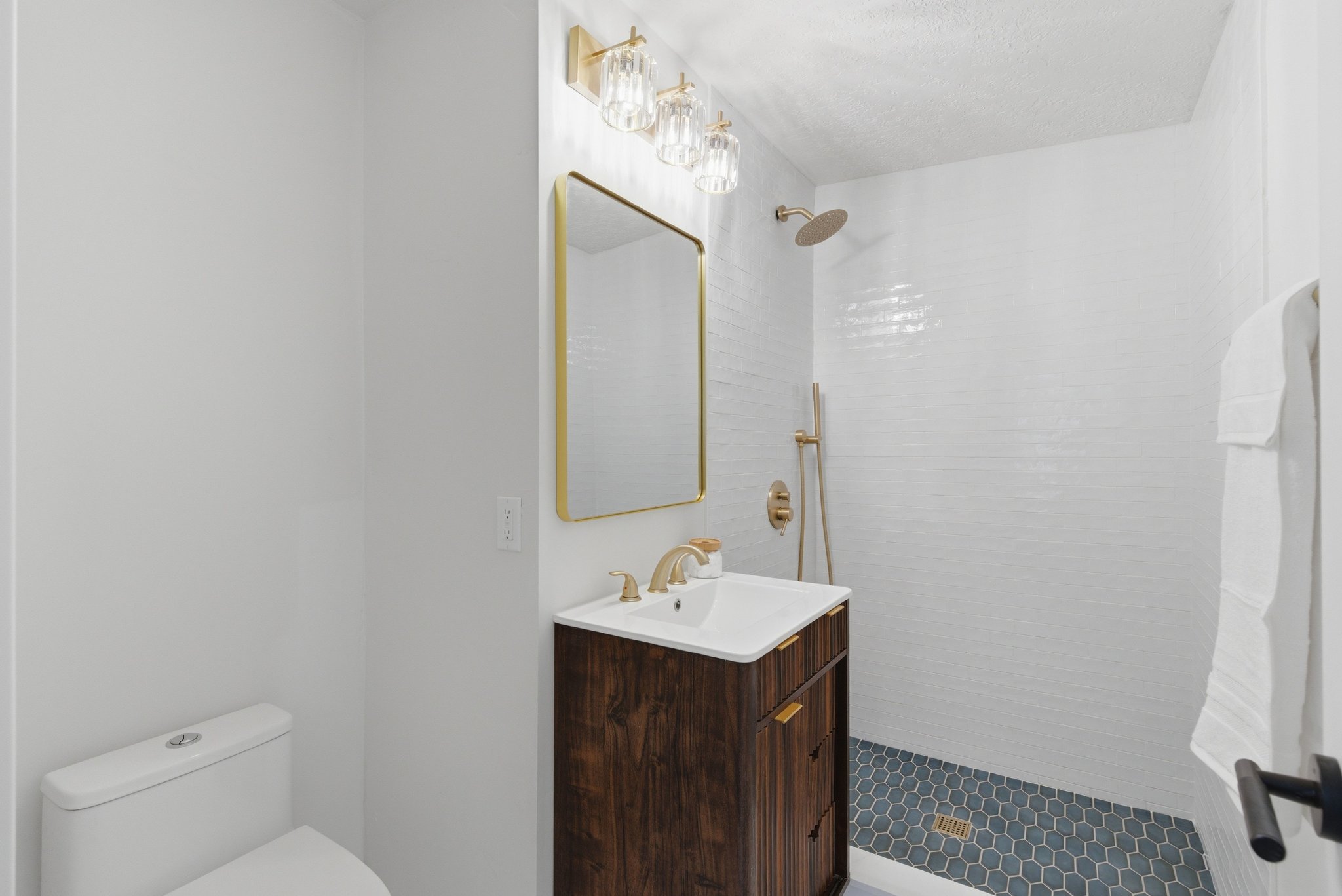 Bathroom featuring a contemporary wood-finish vanity with an integrated sink, gold-tone faucet, and rectangular mirror