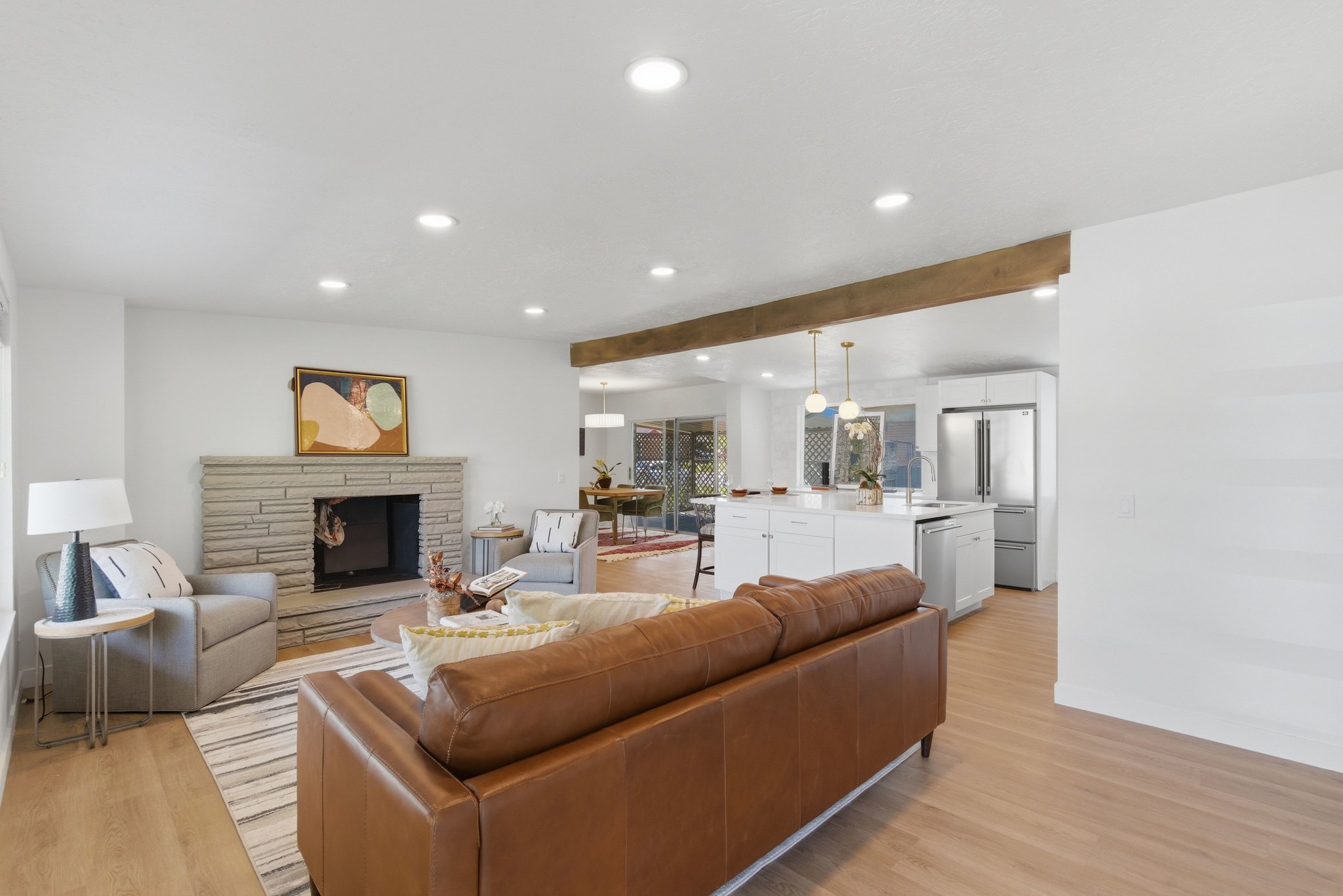 Spacious living area featuring light wood-finish flooring, recessed lighting, and a stacked stone fireplace