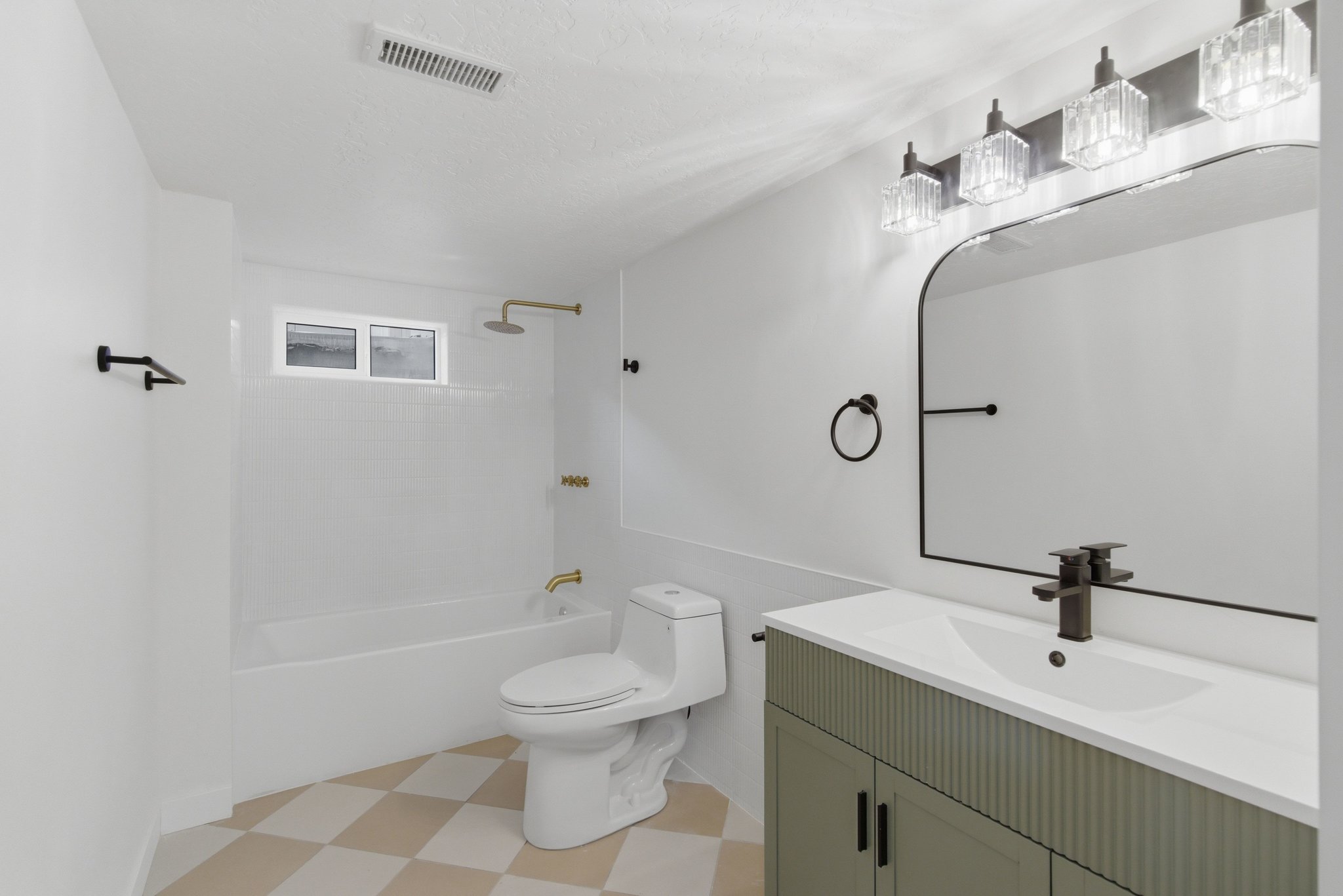 Bathroom featuring a white bathtub with gold-tone fixtures, a toilet, and a vanity with a fluted sage green cabinet