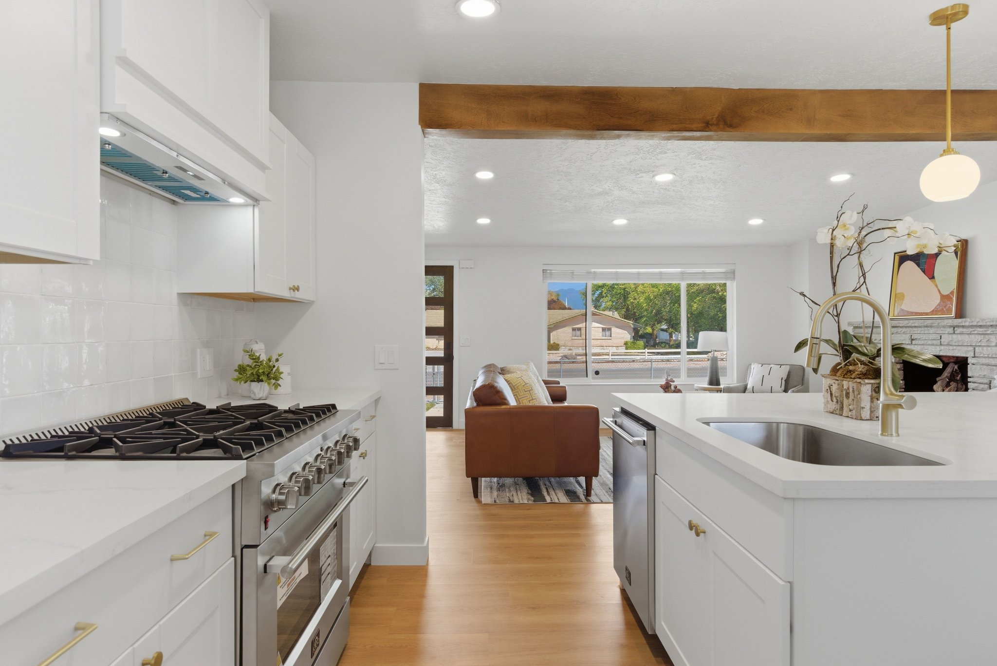 Bright kitchen featuring white cabinetry, a stainless steel range, white subway tile backsplash, and a large island with an undermount sink and gooseneck faucet