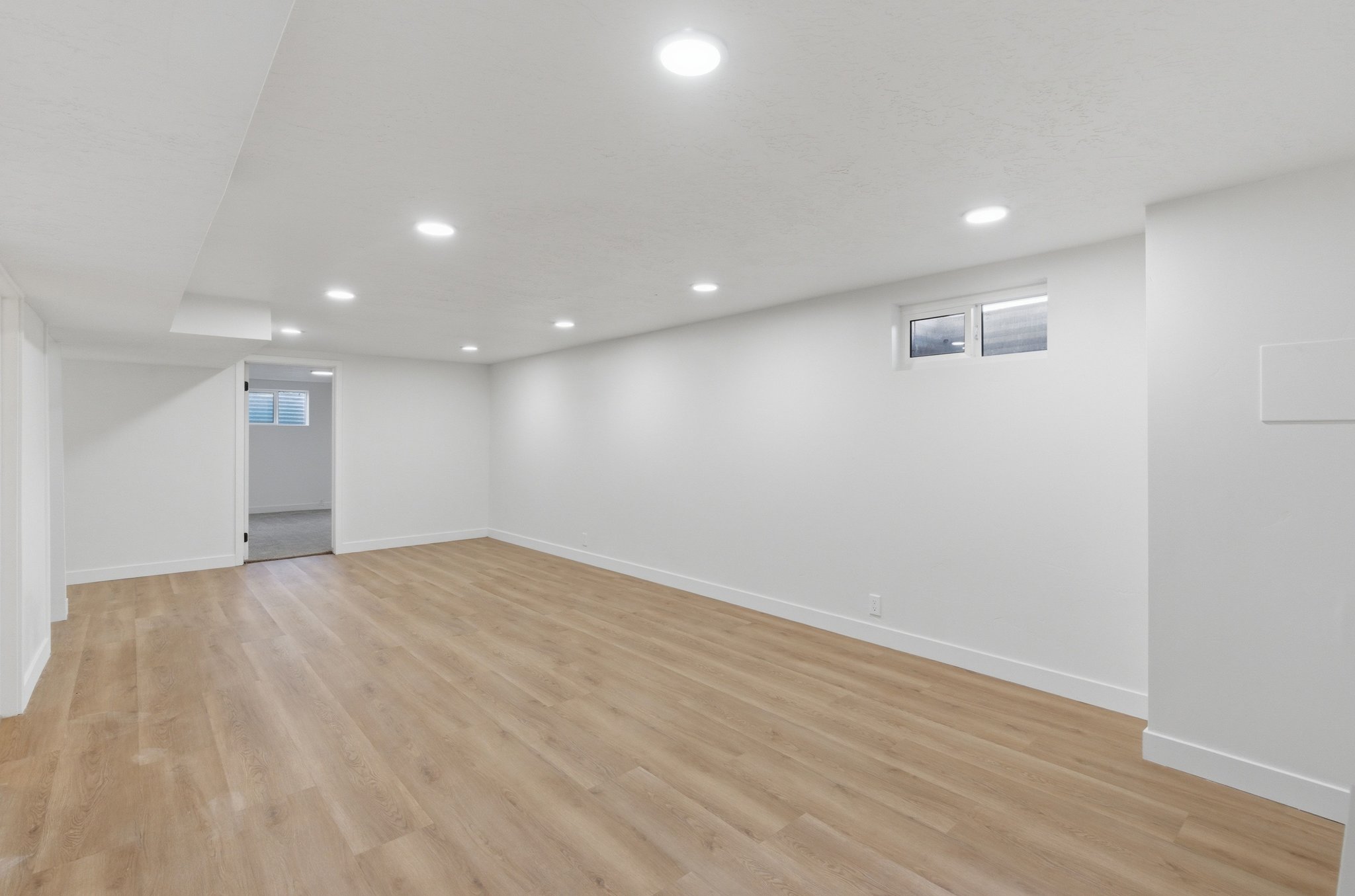 Expansive interior space featuring wood-finish flooring, recessed lighting, and white baseboards