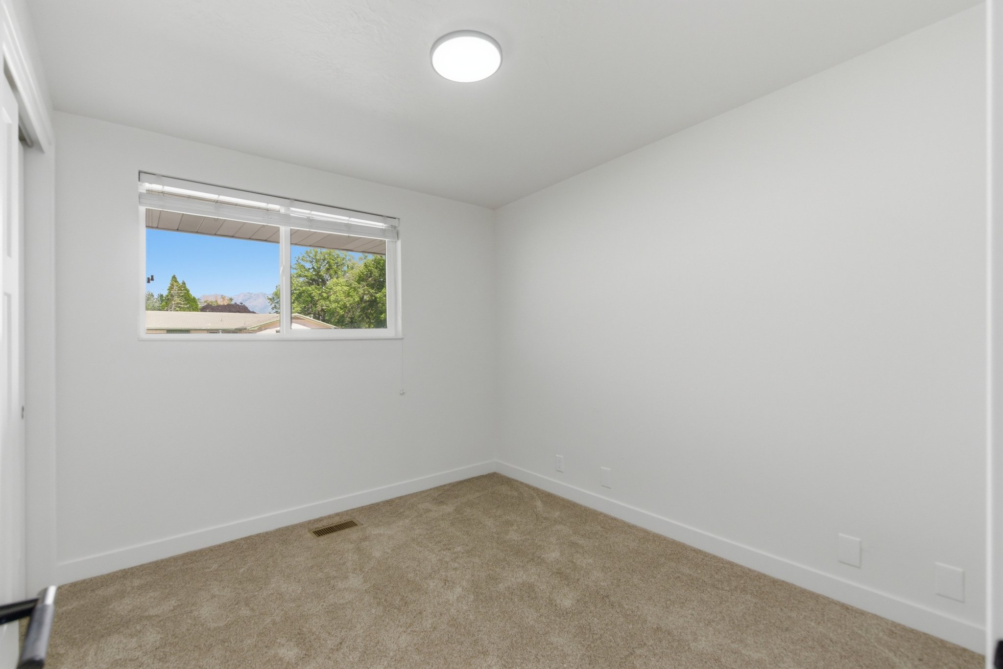 Room featuring light-colored carpet flooring, white walls, and a white ceiling with a flush-mount light fixture