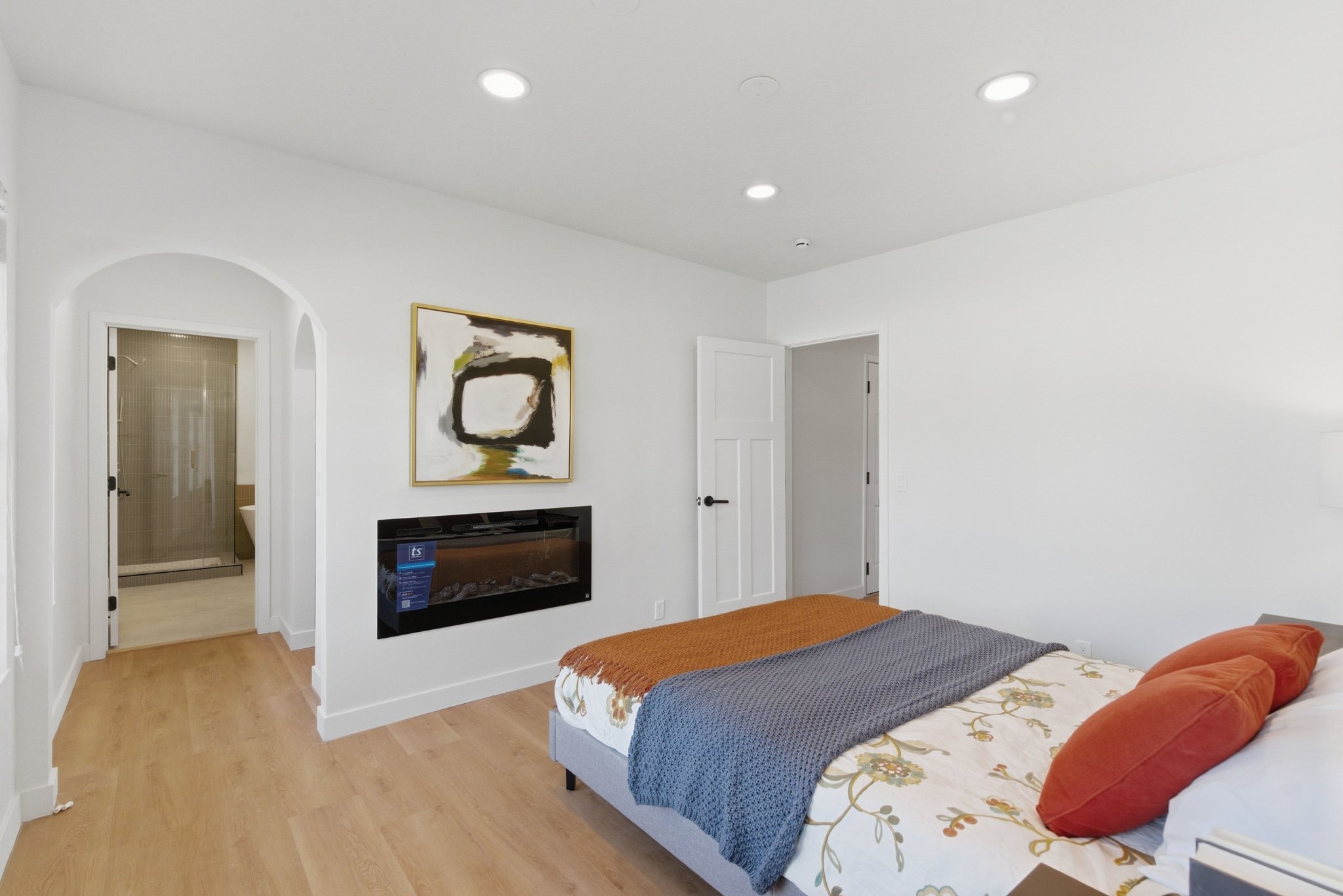 Recessed lighting illuminates a spacious room featuring wood-finish flooring and a built-in electric fireplace